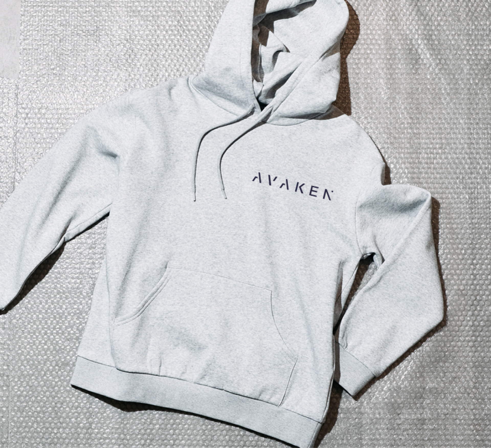 A grey hoodie printed with a studio logo
