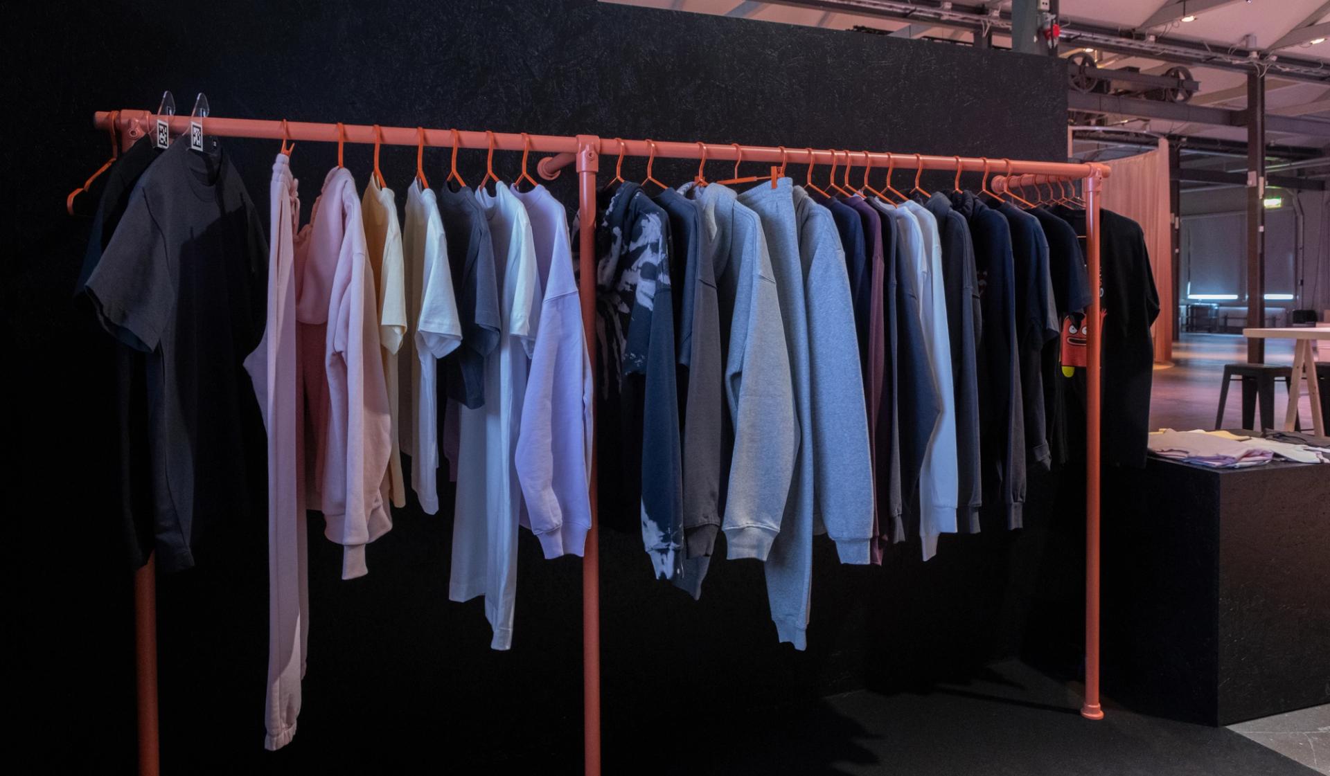 A rack of premium print on demand apparel hangs on red hangers