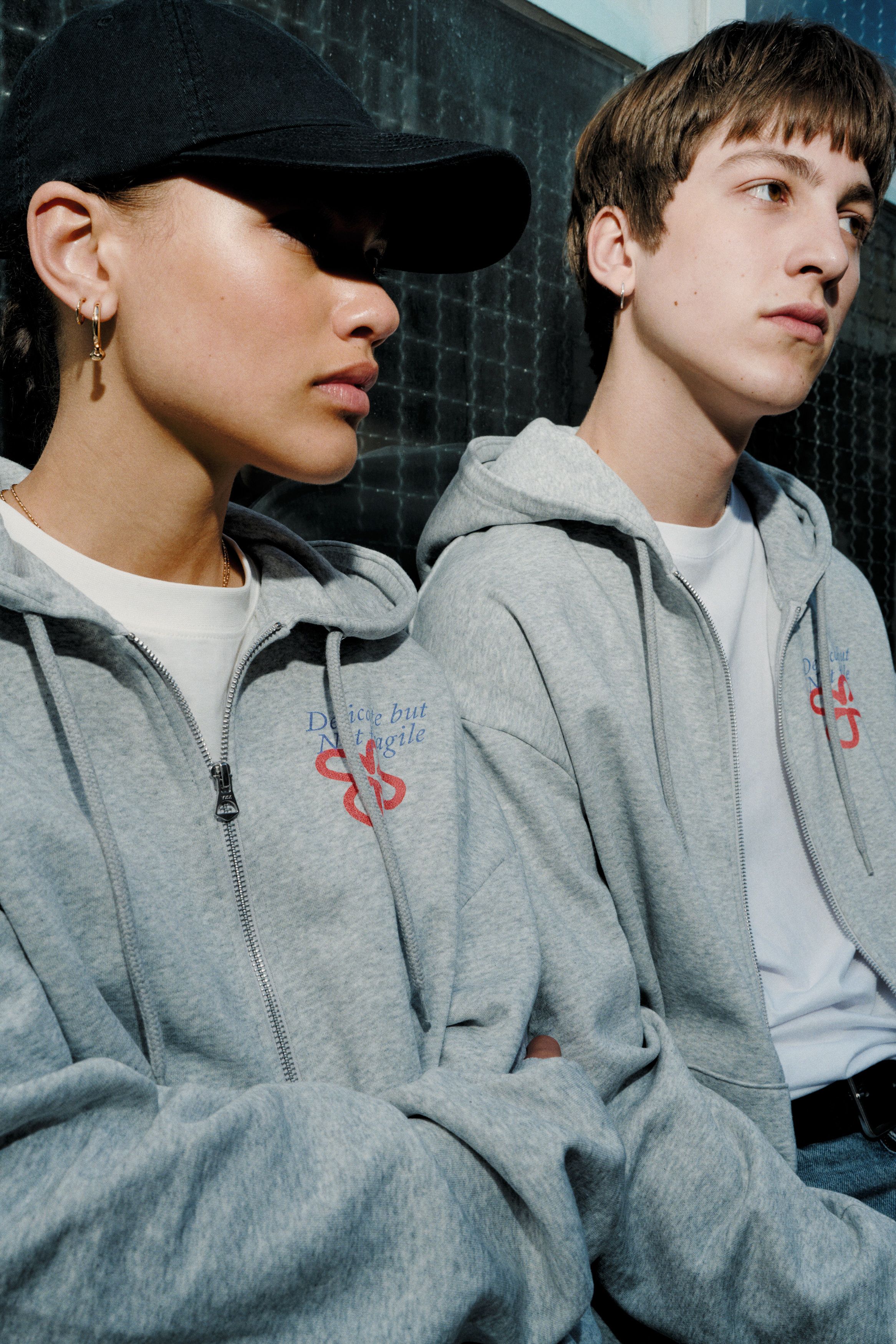 Two models wearing the same zip hoodie with a chest print
