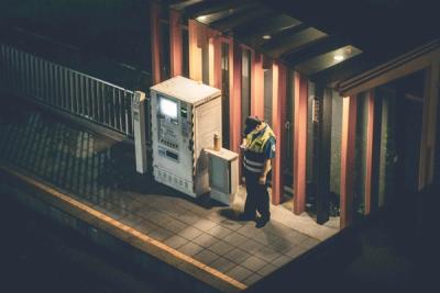 A security officer in a high-visibility vest checking a building's gate on the night shift
