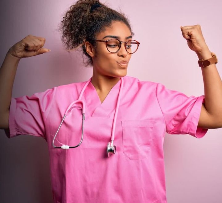 Sam, a nursing assistant in pink scrubs, celebrating