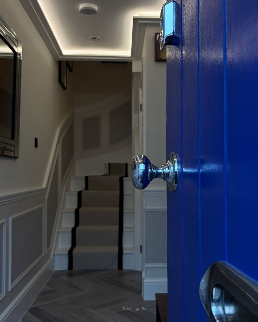 Looking in from the blue front door: panelled hallway, herringbone flooring and the carpeted staircase.
