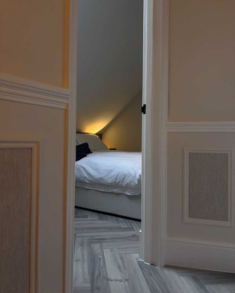 Through the panelled landing into the finished loft bedroom.