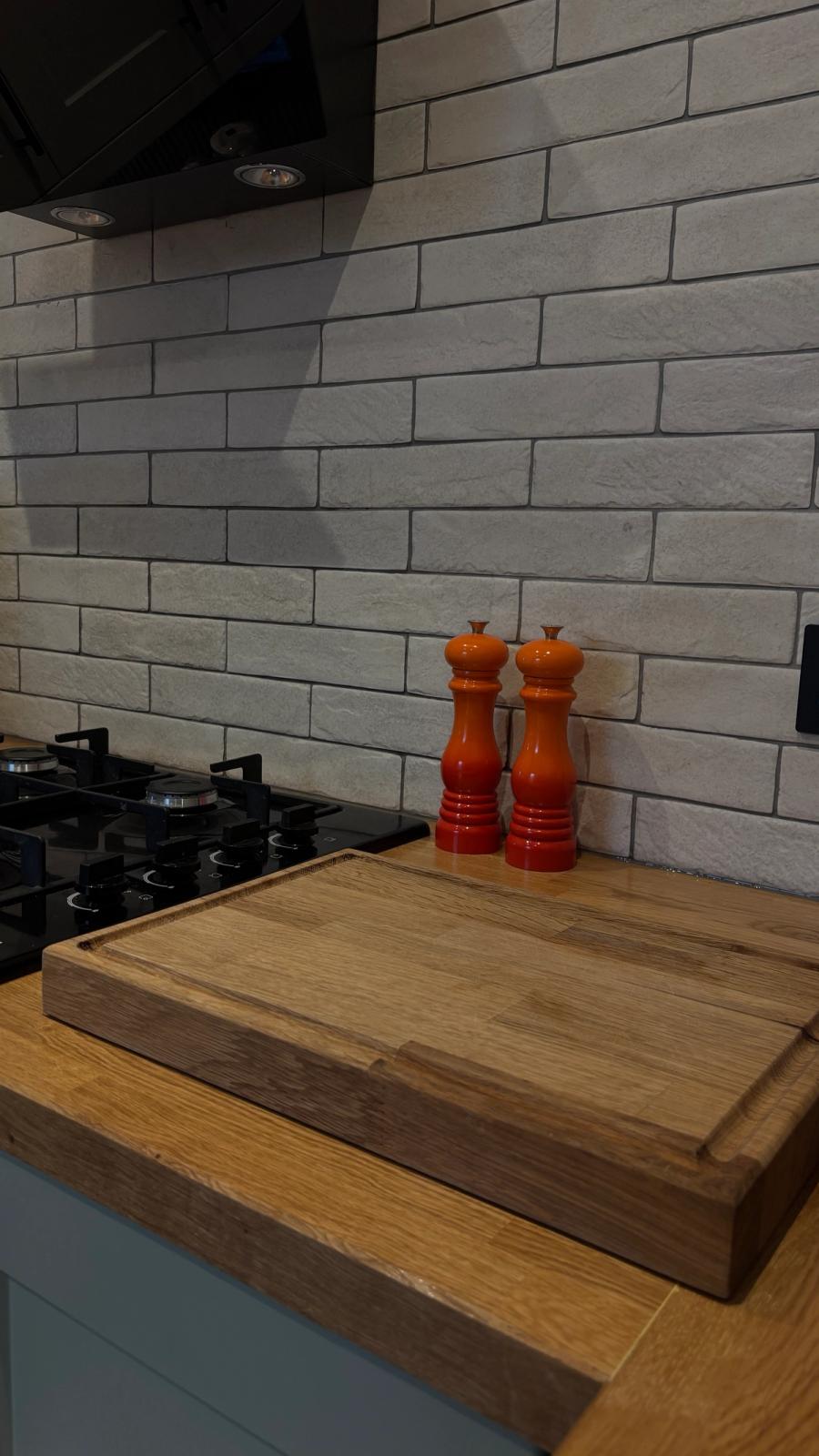 Kitchen detail: the solid oak worktop and chopping block against a white brick-tiled splashback.