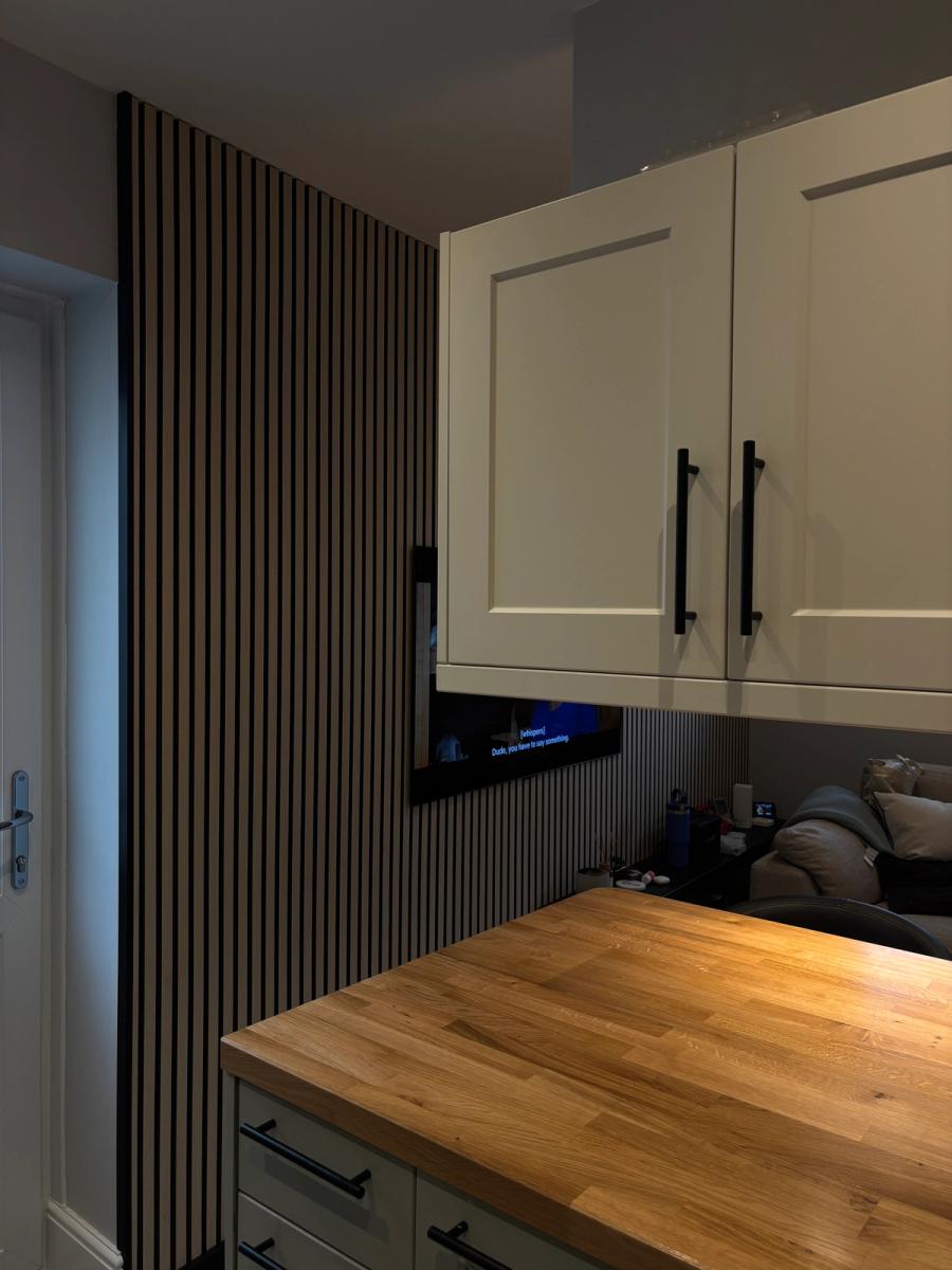 Cream shaker wall cabinets beside the reeded oak feature wall and its inset television.