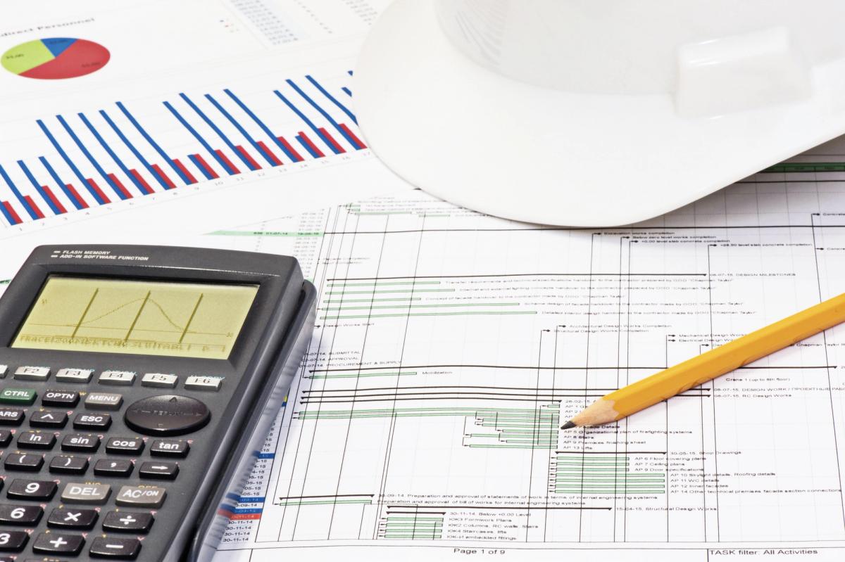 A calculator, cost charts and a project programme used to plan, price and schedule a residential build.
