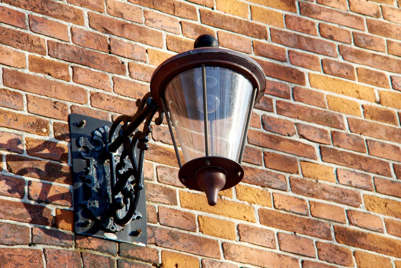 A traditional lantern on a handmade brick wall, weathered and better for it.