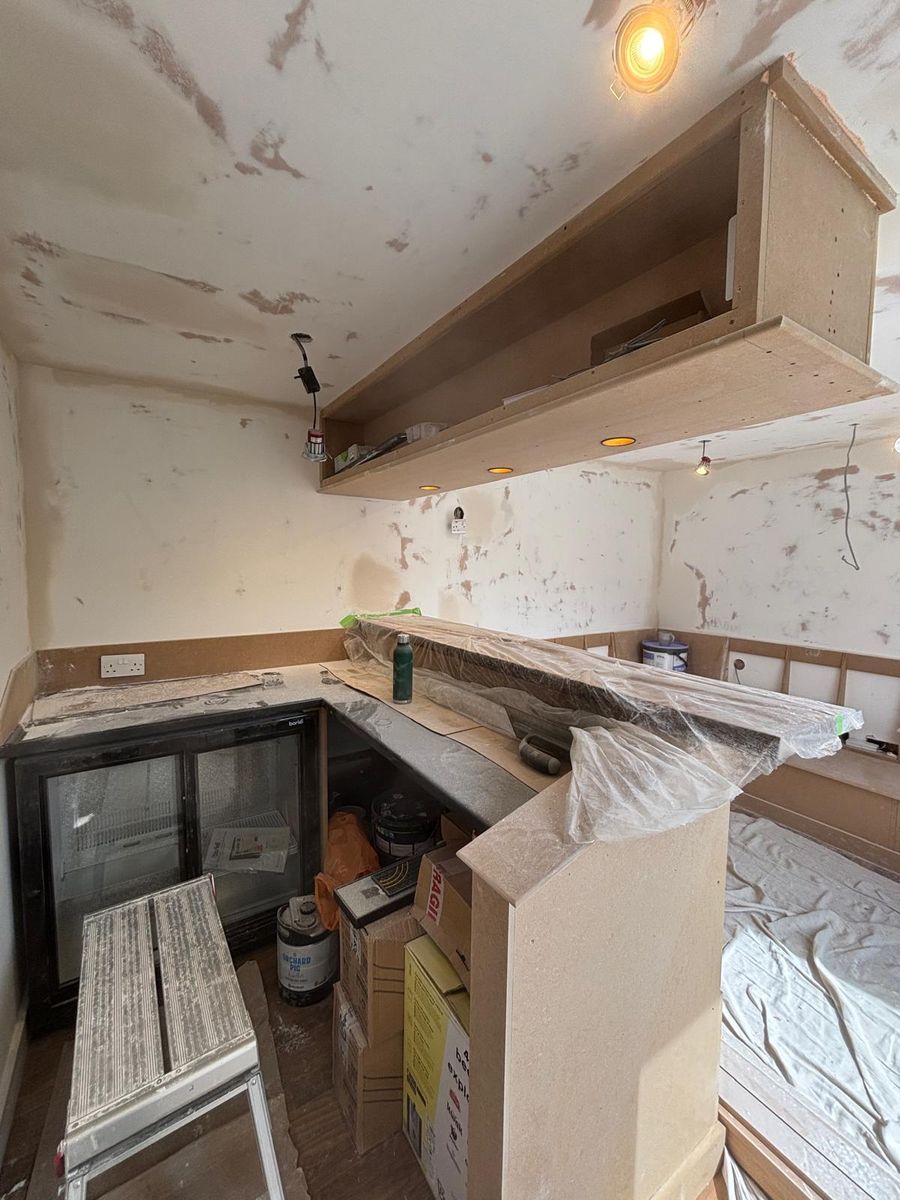 First fix: back-bar shelving up and the drinks fridge in position, the worktop under wraps.