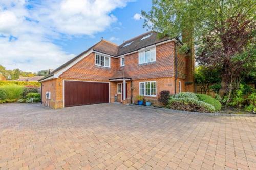 A tile-hung detached family home in Tadworth, Surrey, with a block-paved drive and double garage.