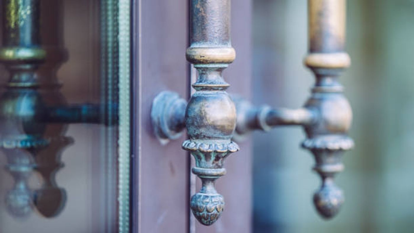 Patinated bronze door fittings, softened by years of use.