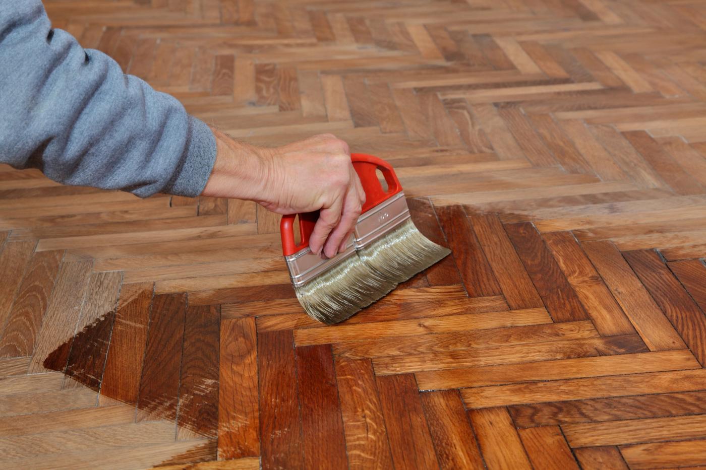 Herringbone parquet mid-restoration, oil bringing the oak back to life.