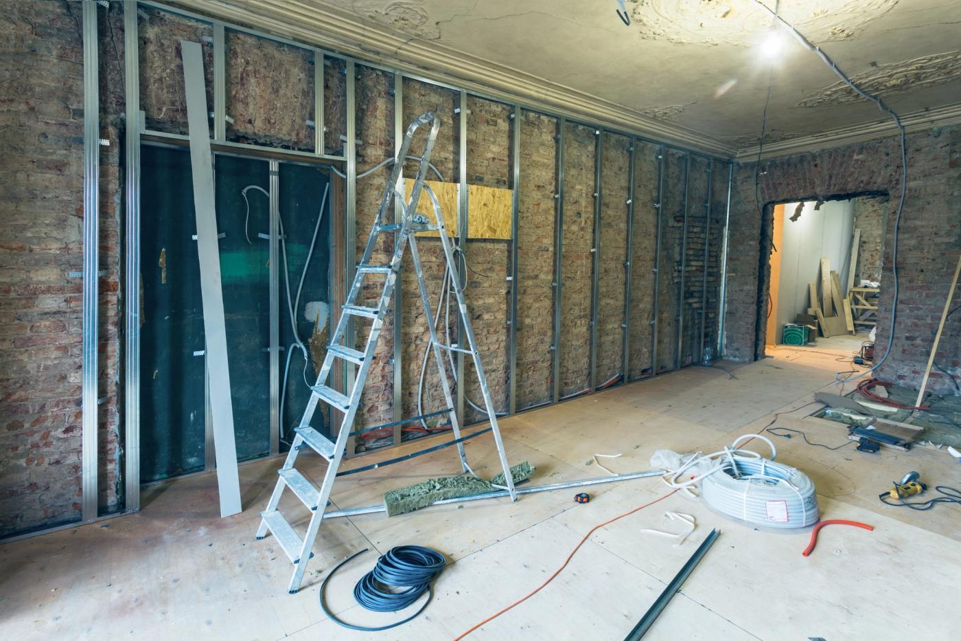 A room stripped back to its structure, with studwork and first-fix services exposed.