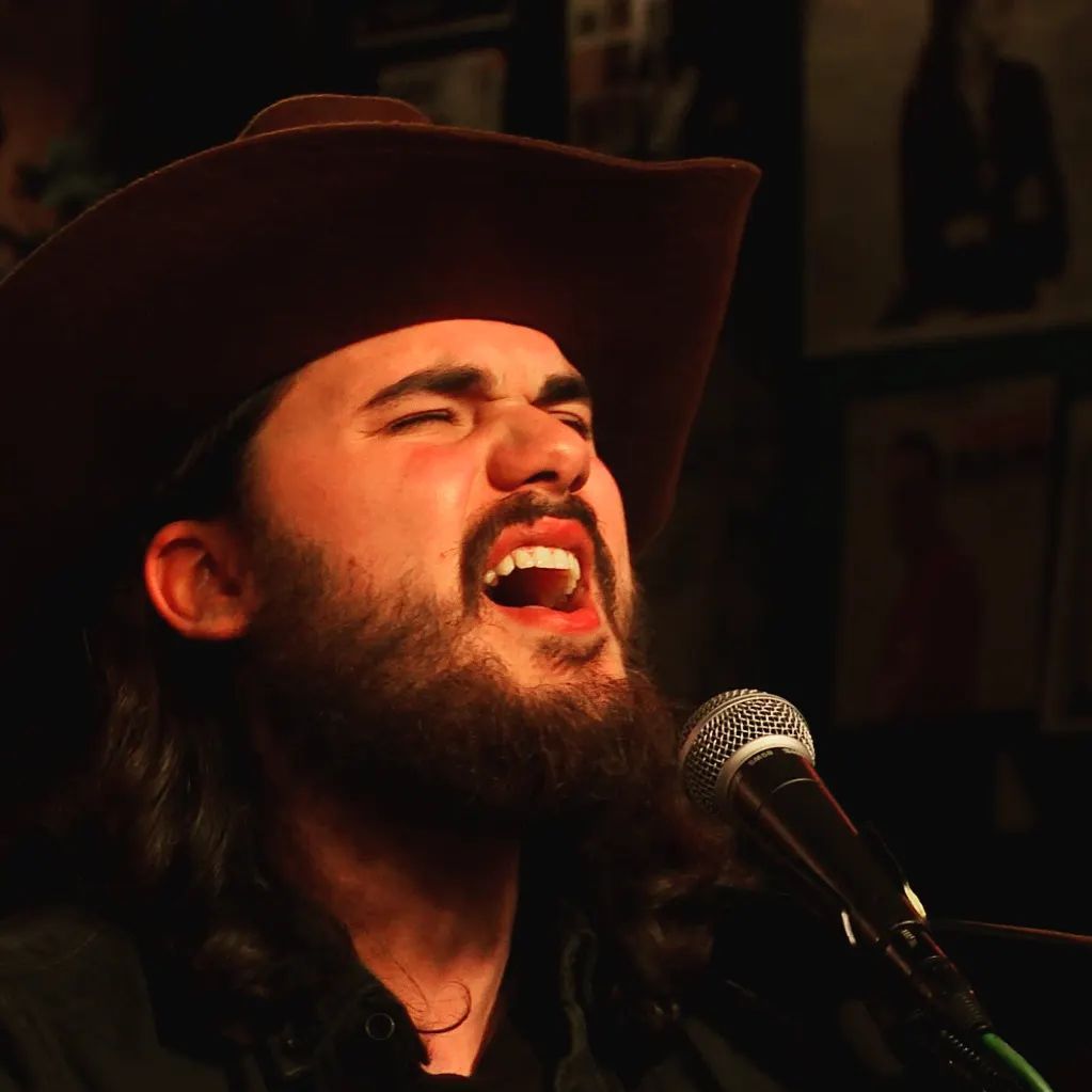 Matheus Granjeiro de chapéu cantando ao microfone
