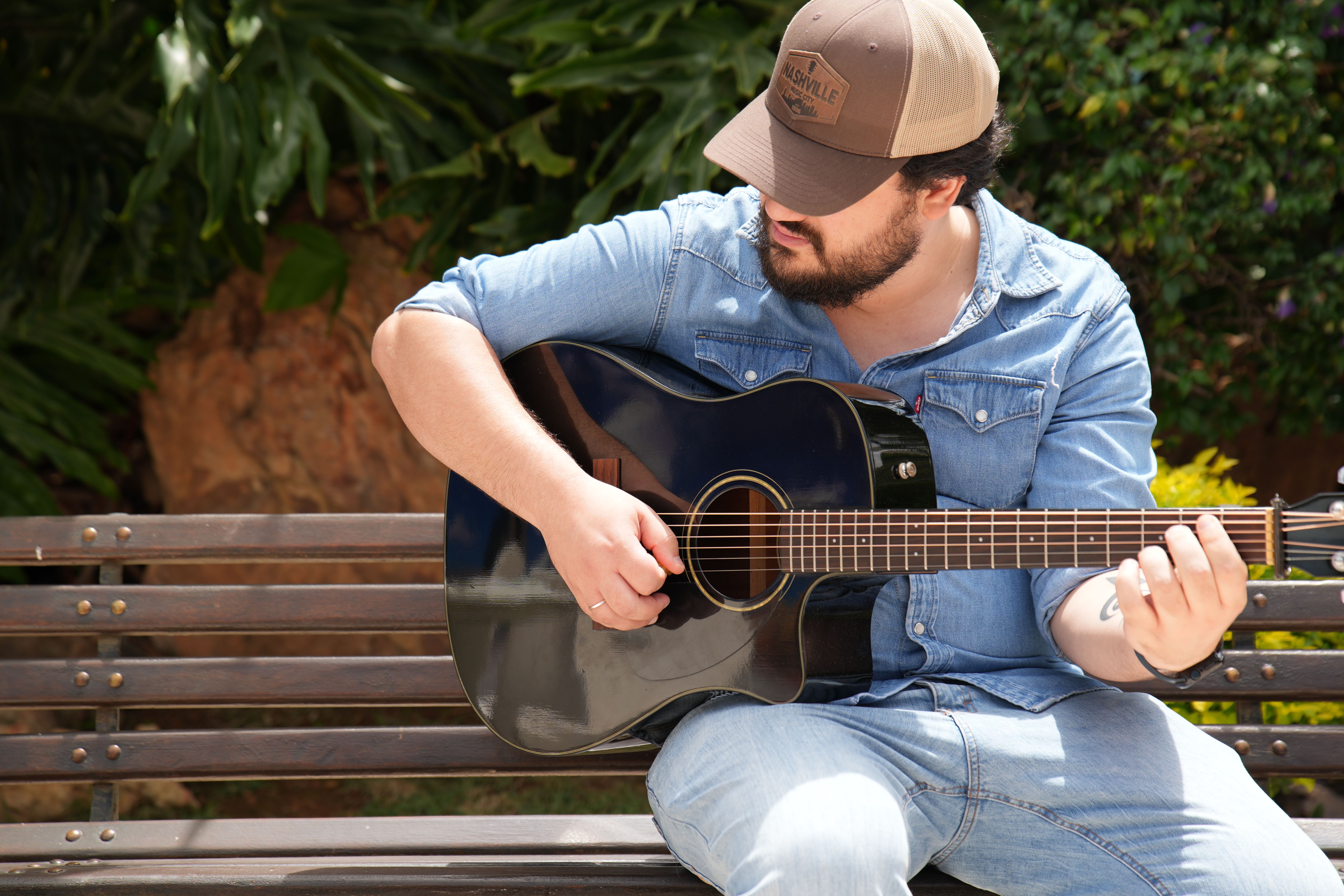 Matheus Granjeiro de boné tocando violão, enquadramento fechado