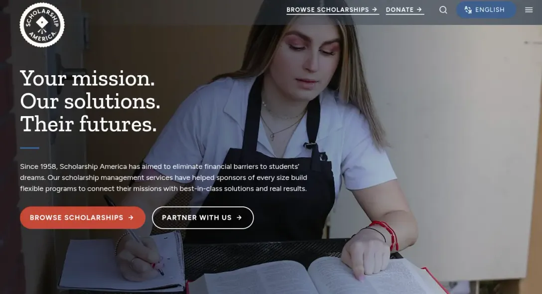 Scholarship America homepage with the headline "Your mission. Our solutions. Their futures." over a student writing in a notebook beside an open book.