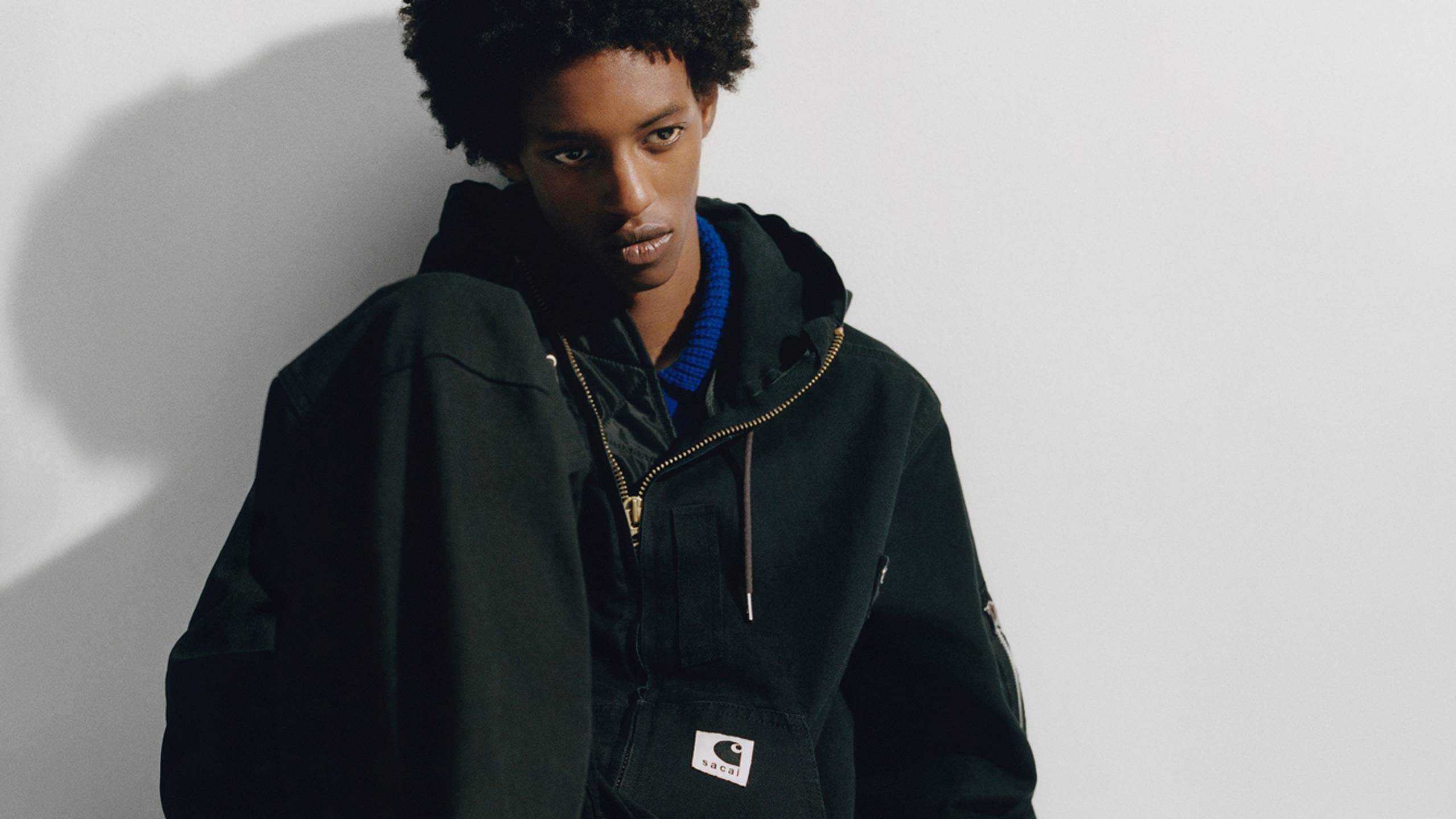 Person wearing a black sacai x Carhartt WIP hooded jacket