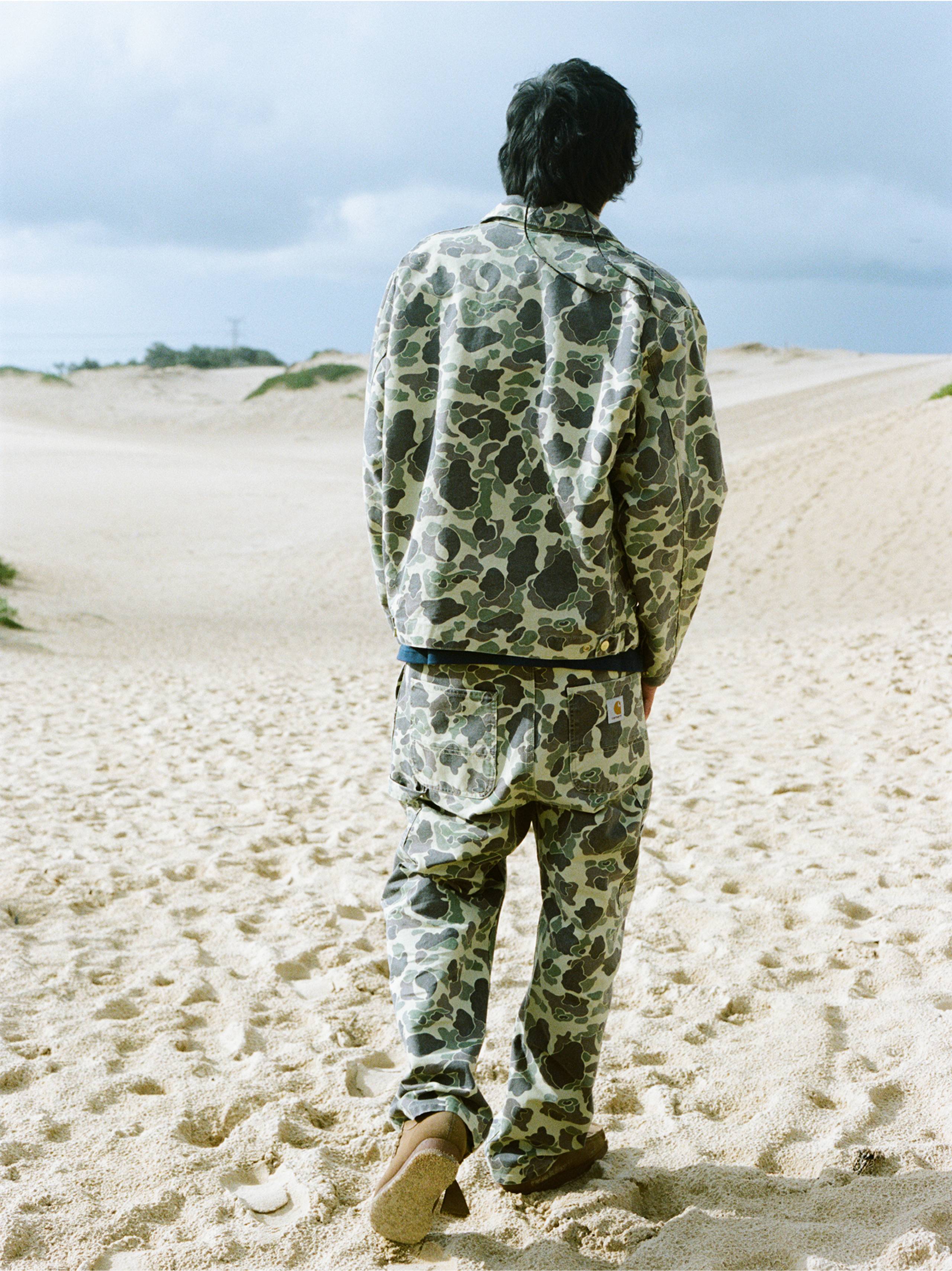 Back view of a person on the beach wearing a camo jacket and camo pants