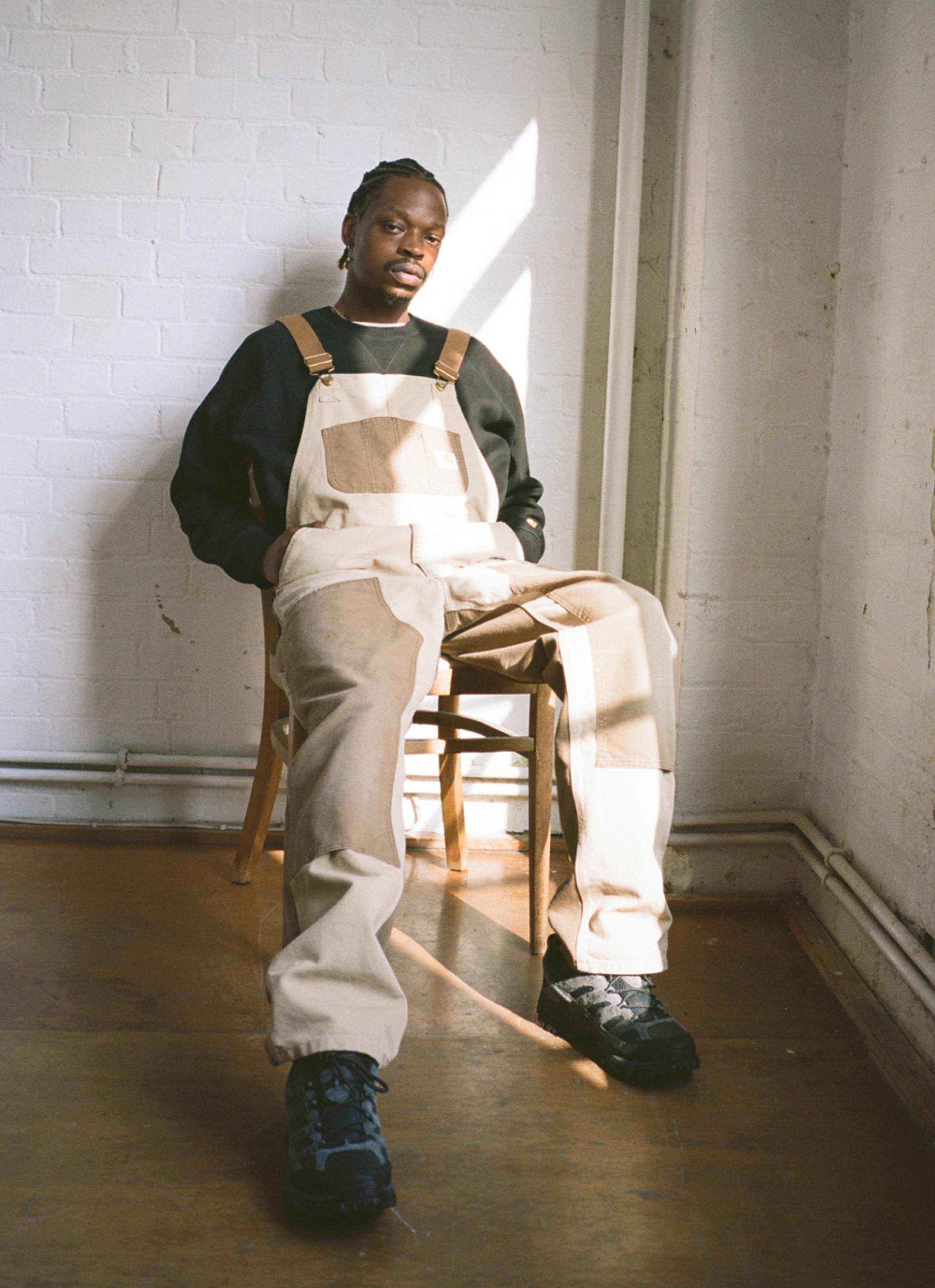 Seated Model wearing Carhartt WIP Double Knee Bib Overall in Two Tone Dusty Hamilton Brown