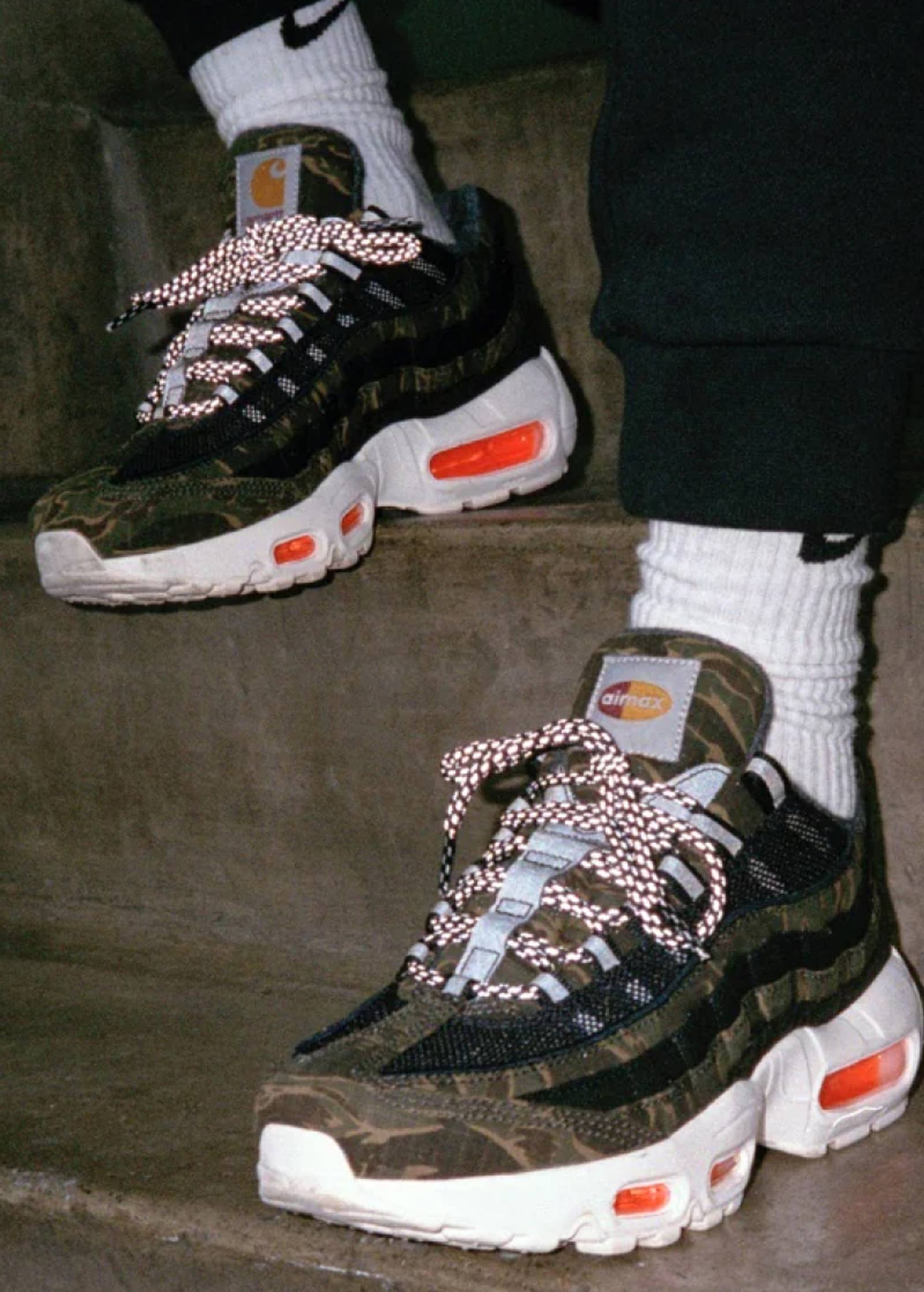 Model wearing Camo Carhartt WIP x Nike Air Max 95 sneakers in a staircase