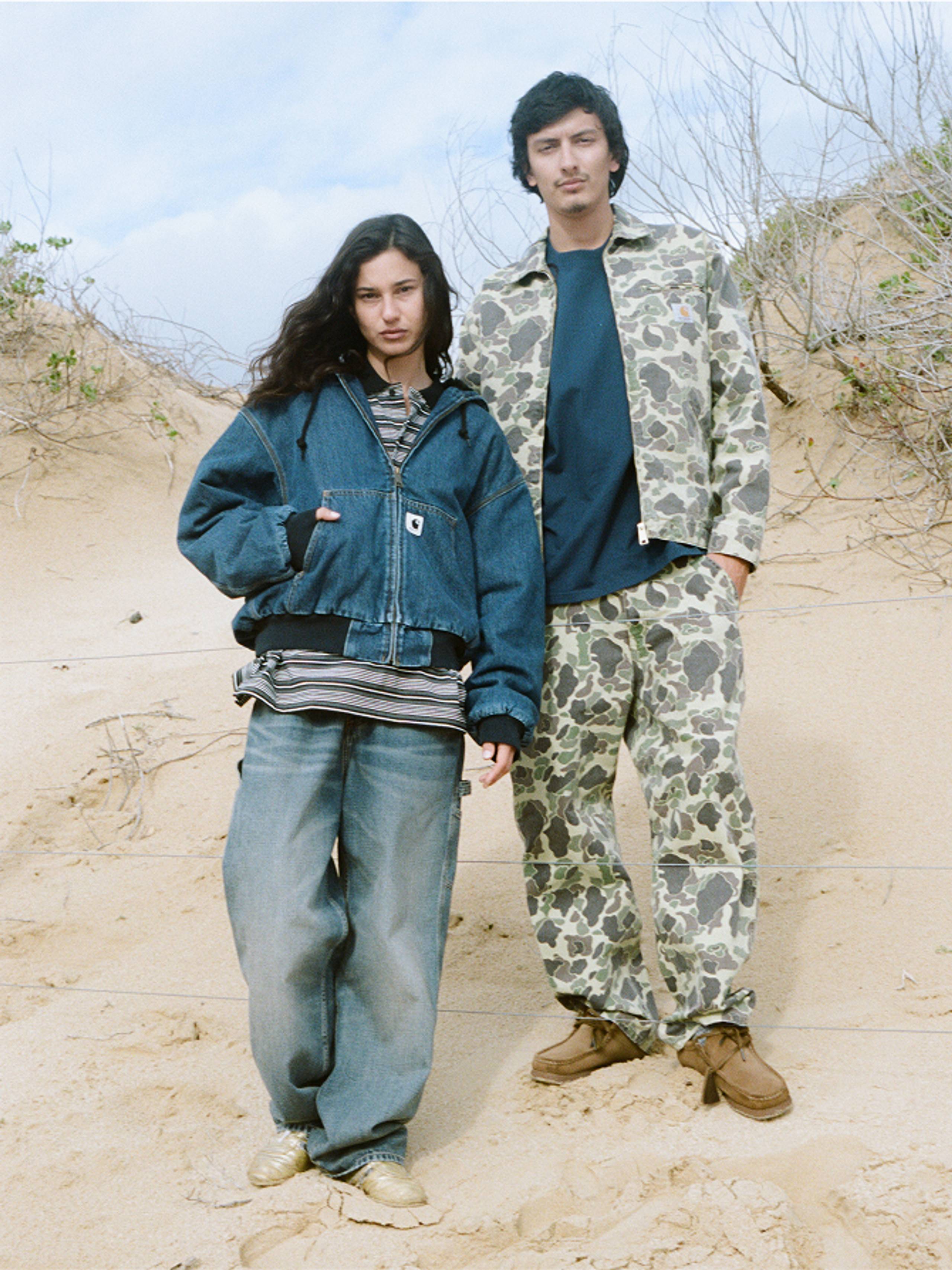 Person on the left wearing a denim active jacket with jeans, person on the right wearing a camo jacket and camo pants