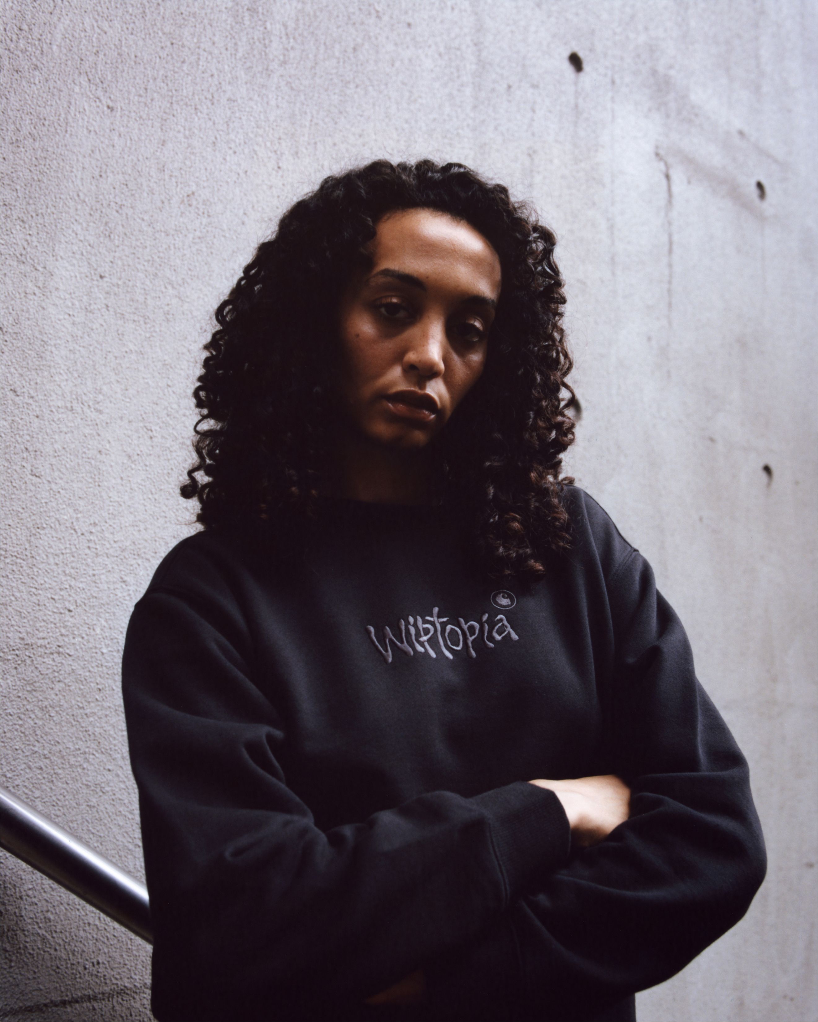 Model posing with arms crossed wearing items from the Carhartt WIP Wiptopia Collection