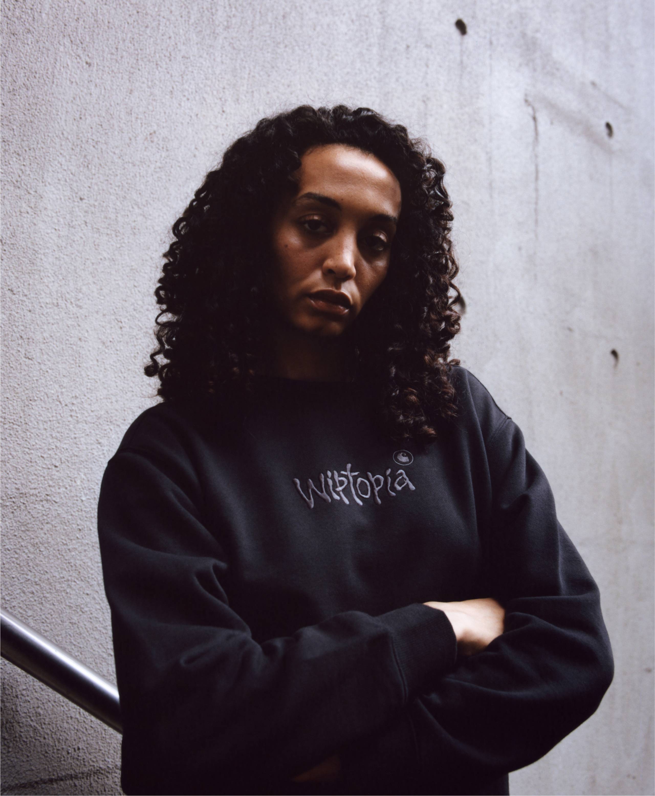 Model posing with arms crossed wearing items from the Carhartt WIP Wiptopia Collection