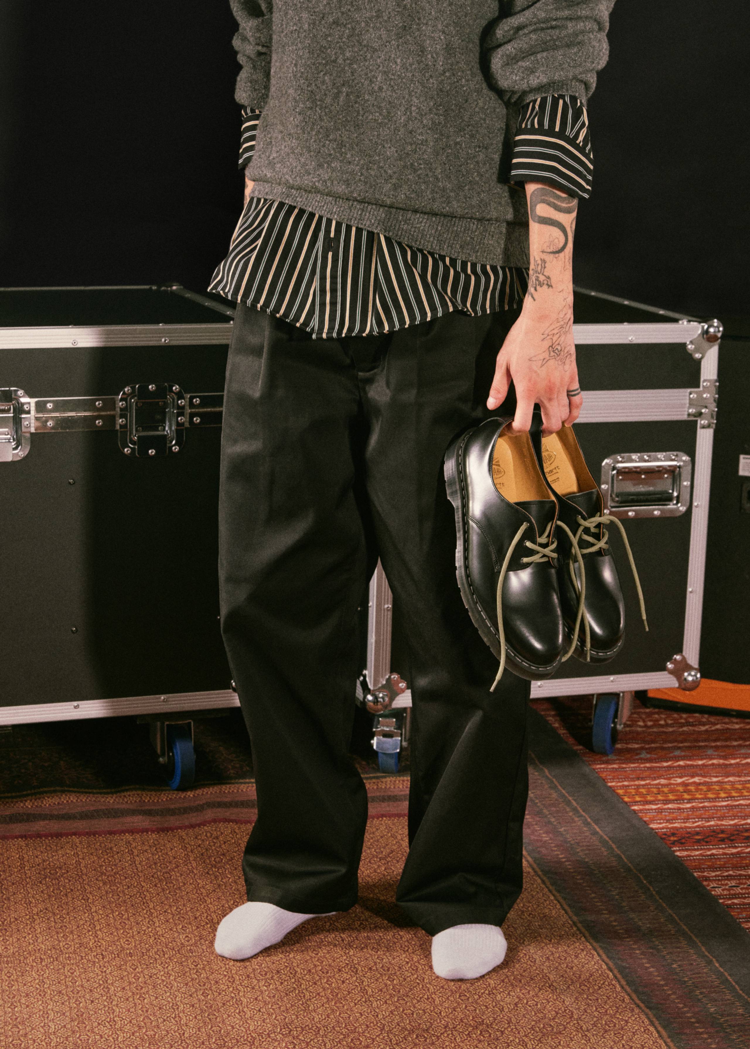Model holding a pair of the Solovair x Carhartt WIP Collaboration Derby shoes in Black