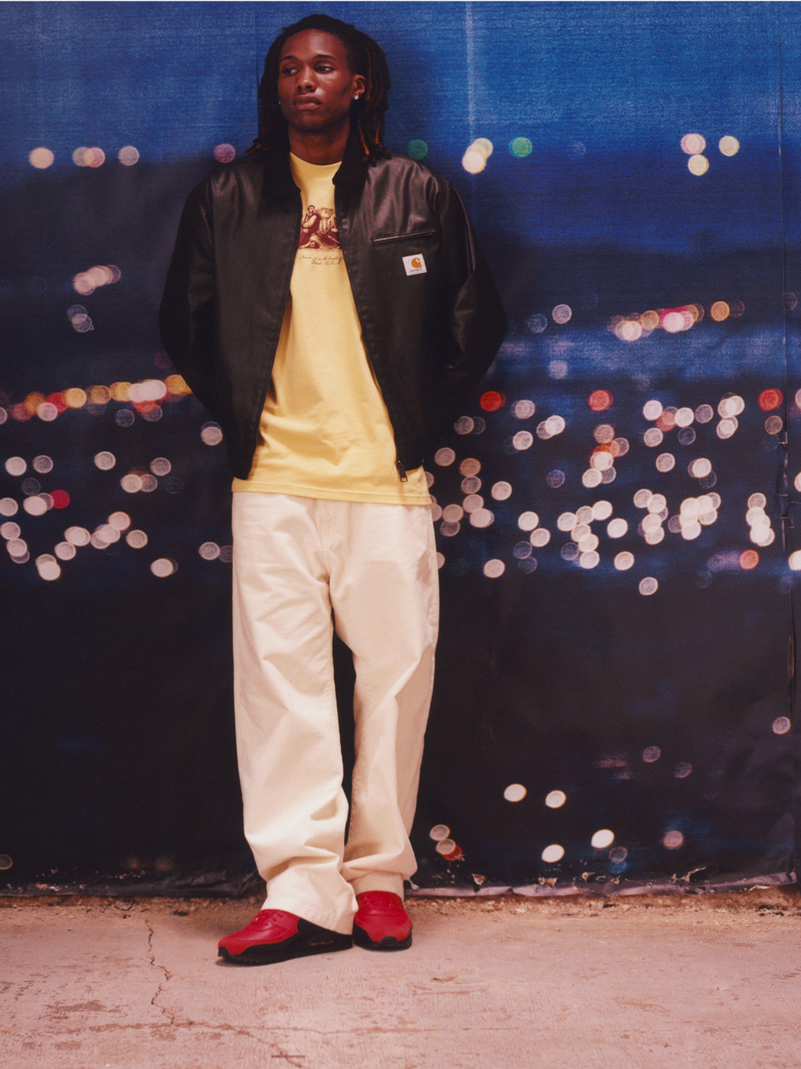 Model wearing a wax coated detroit jacket in black and white pants in the Carhartt WIP F/W25 Men's Lookbook