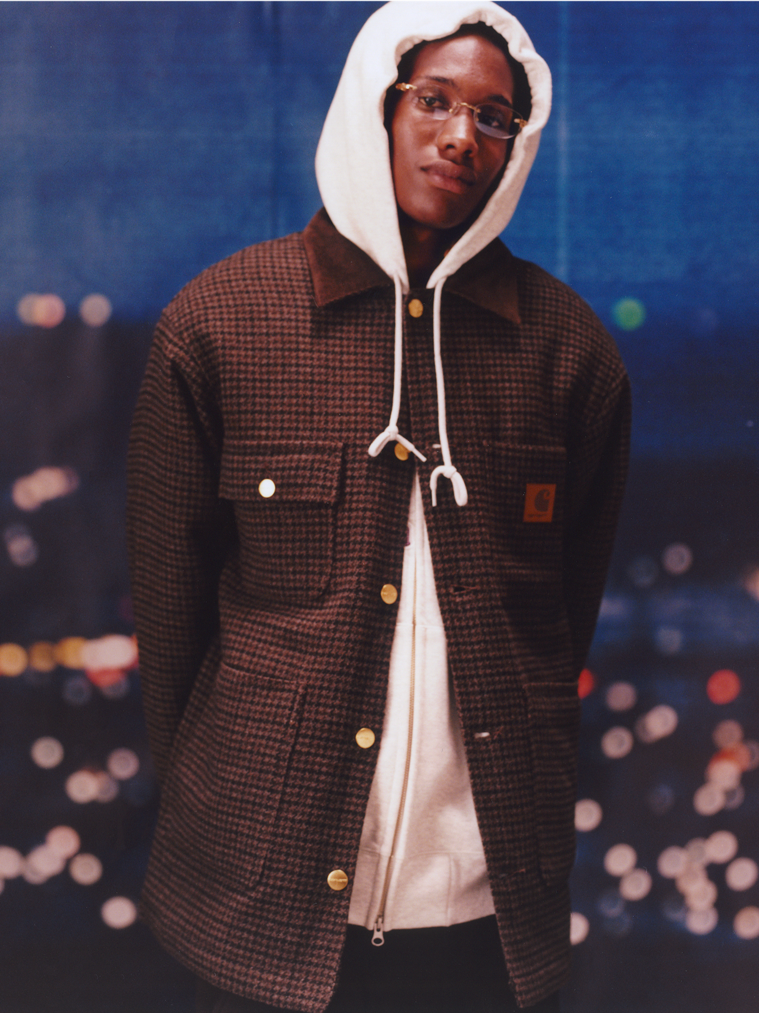 Model wearing a houndstooth coat in the Carhartt WIP F/W25 Men's Lookbook