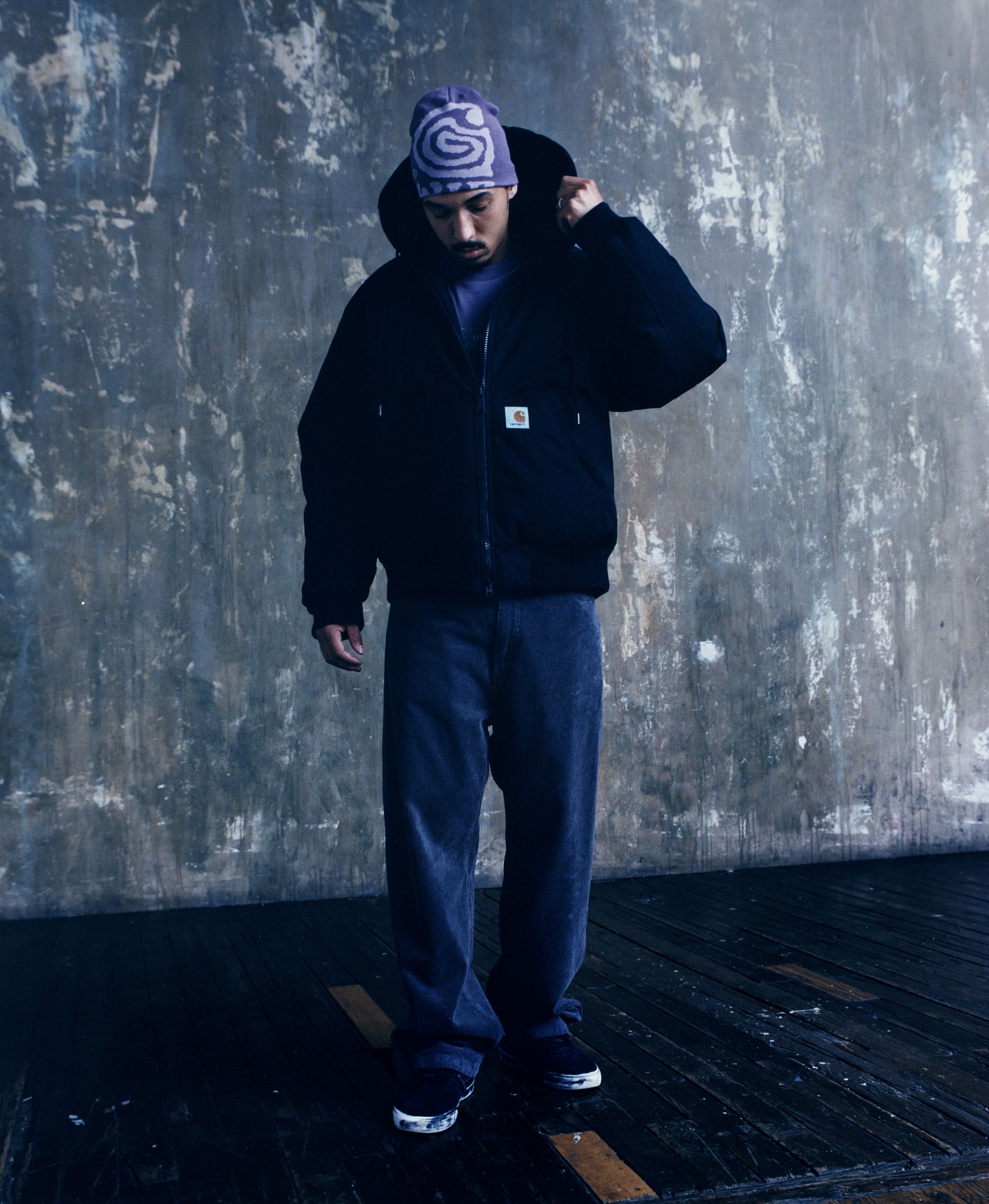 Model standing wearing an OG Active Cold Jacket in Black and a Helix Beanie in Phlox