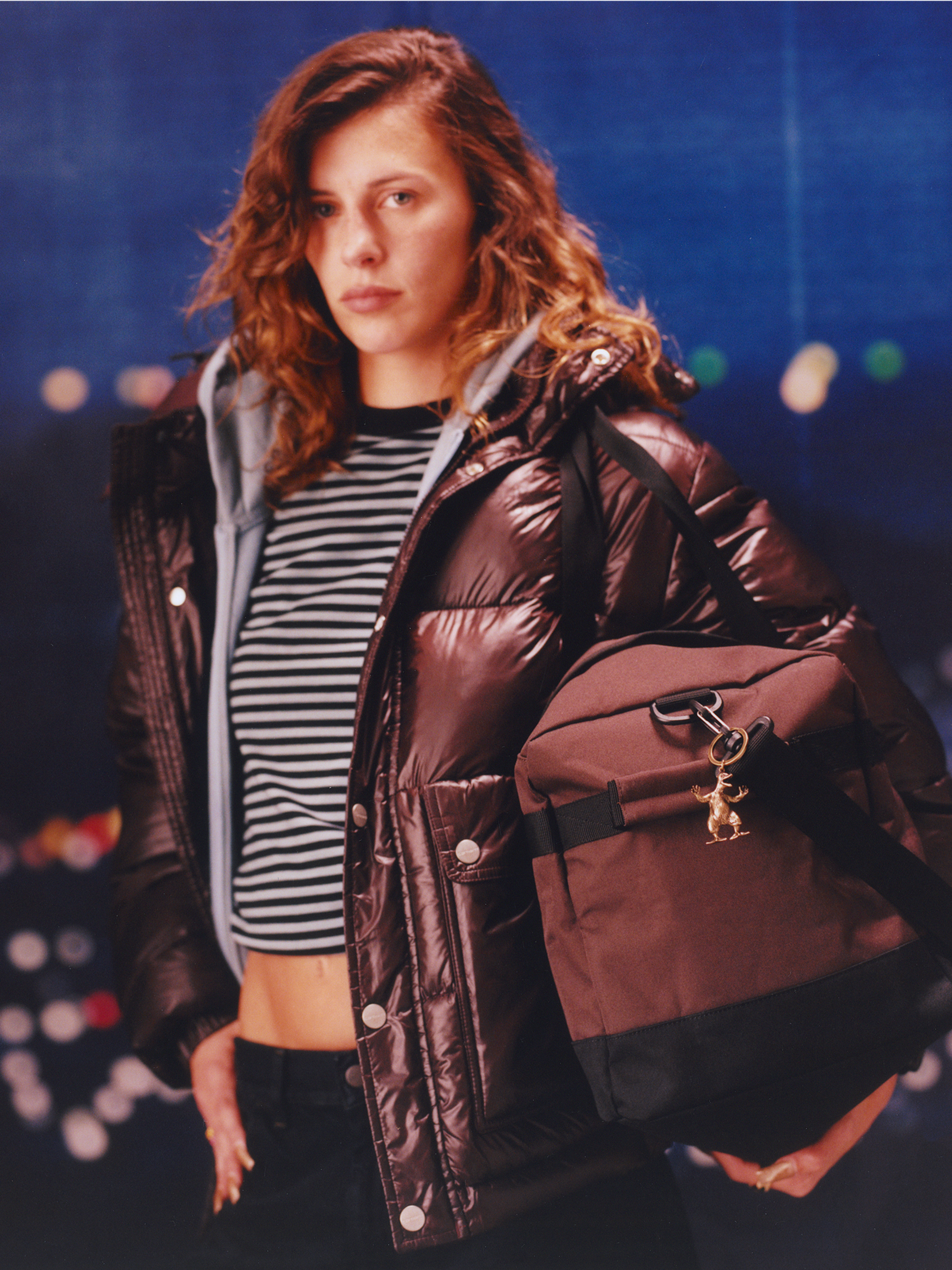 Model wearing a puffer jacket and holding a duffle jacket in the Carhartt WIP F/W25 Women's Lookbook