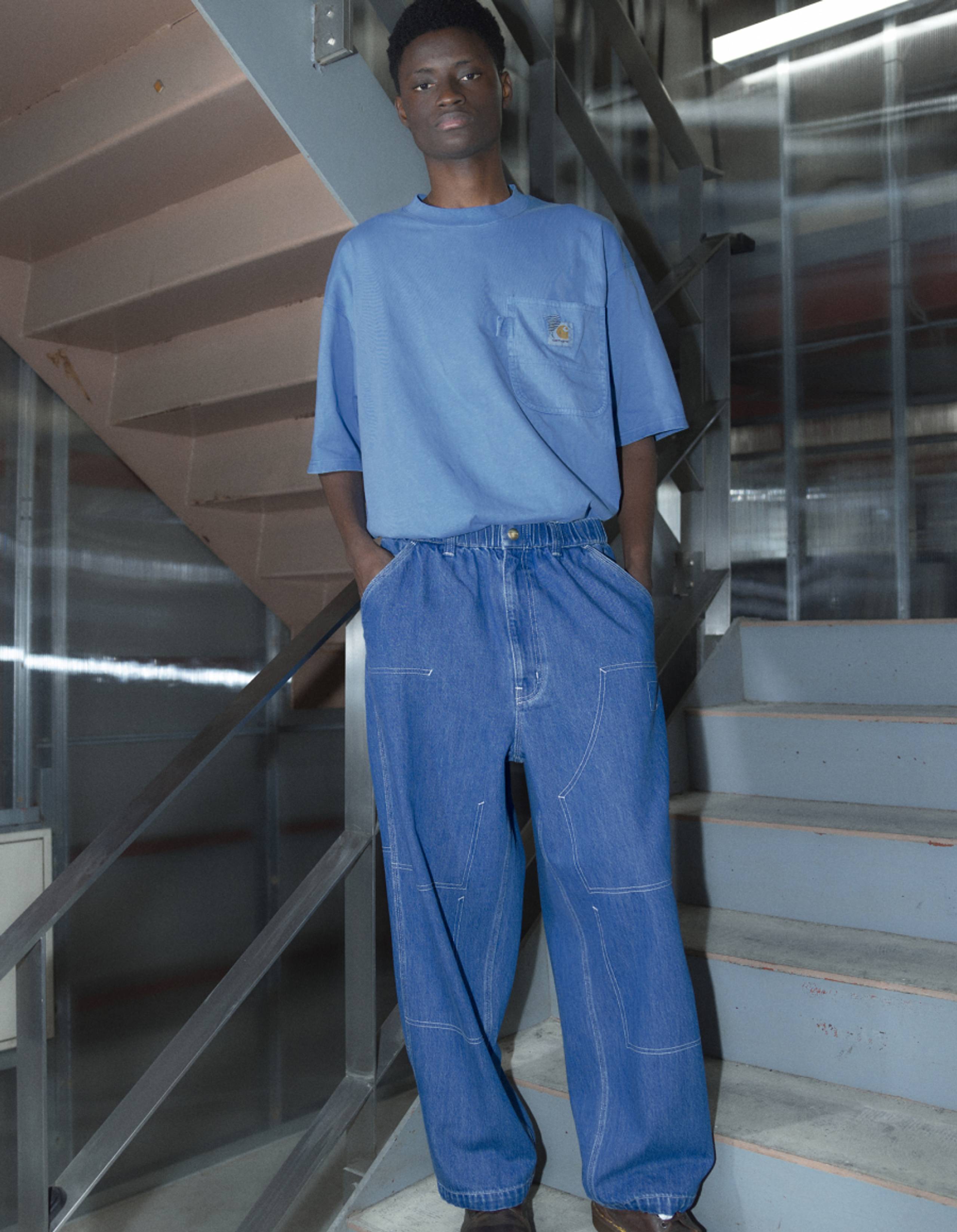 Model wearing Carhartt WIP x INVINCIBLE® Denim Double Knee Pants & Pocket T-shirt