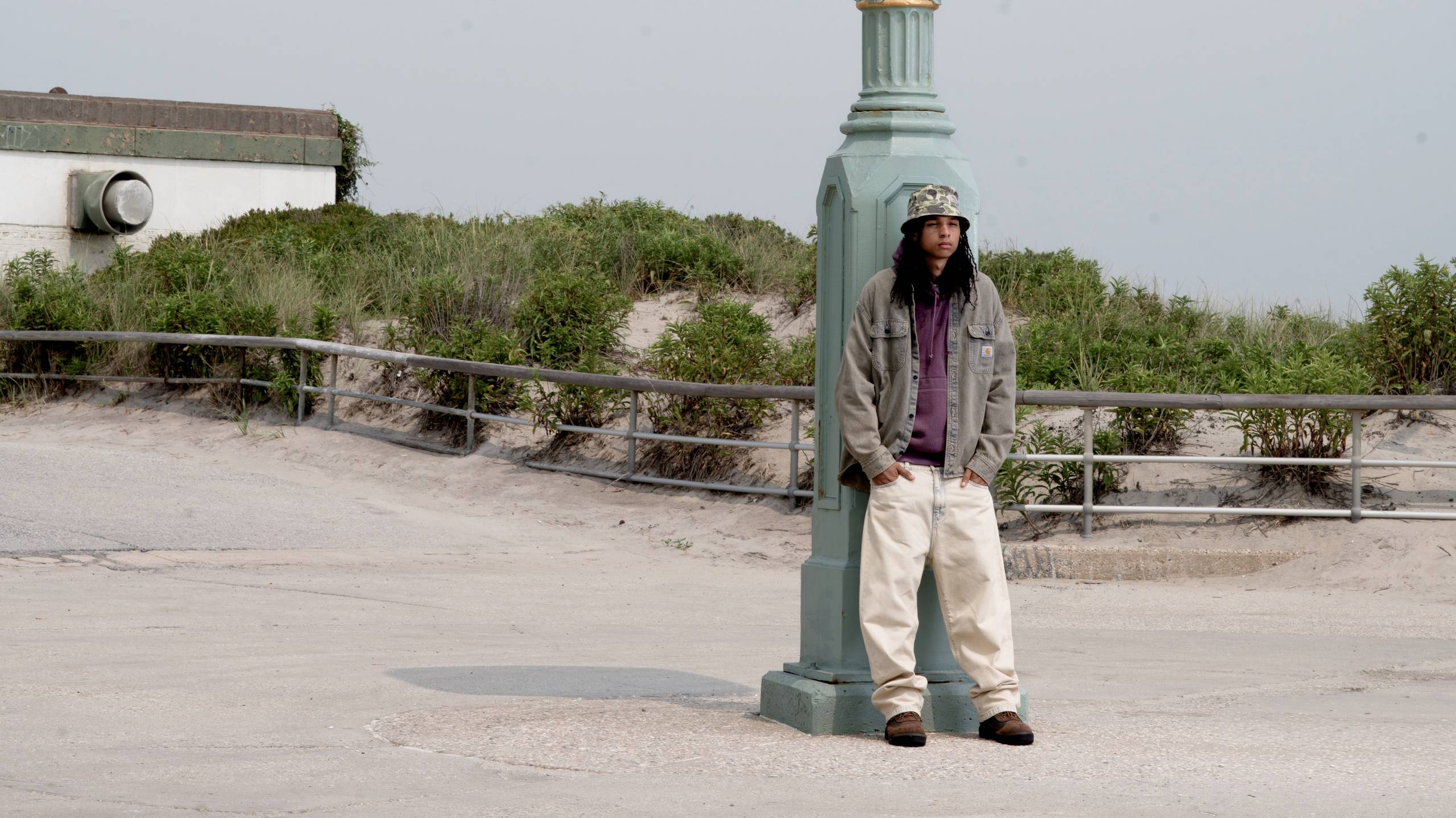 Model wearing a Tigan Shirt Jacket in Blue Garment Dyed and Landon Pant in Blue Sand Bleached in a parking lot