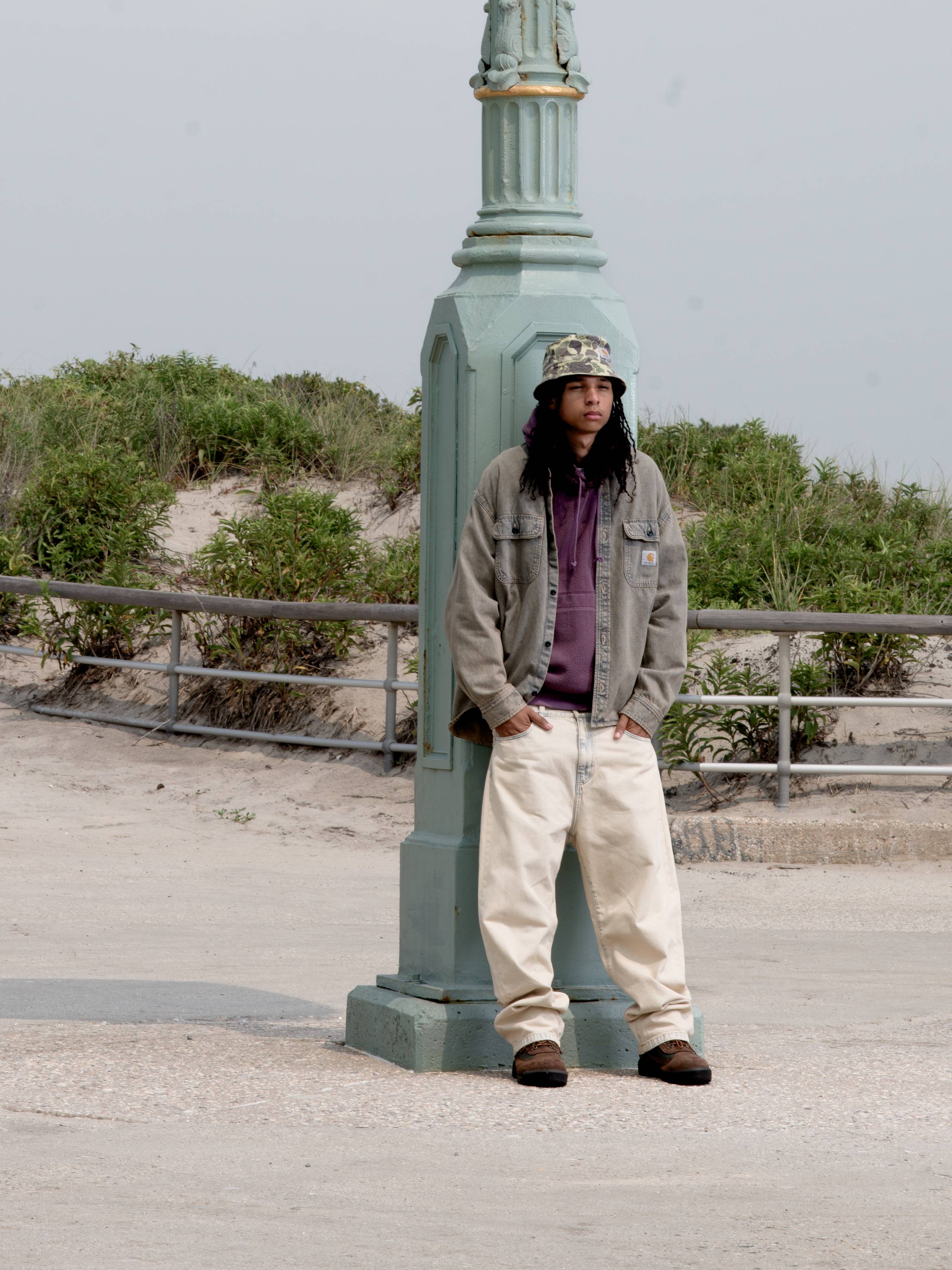 Model wearing a Tigan Shirt Jacket in Blue Garment Dyed and Landon Pant in Blue Sand Bleached in a parking lot