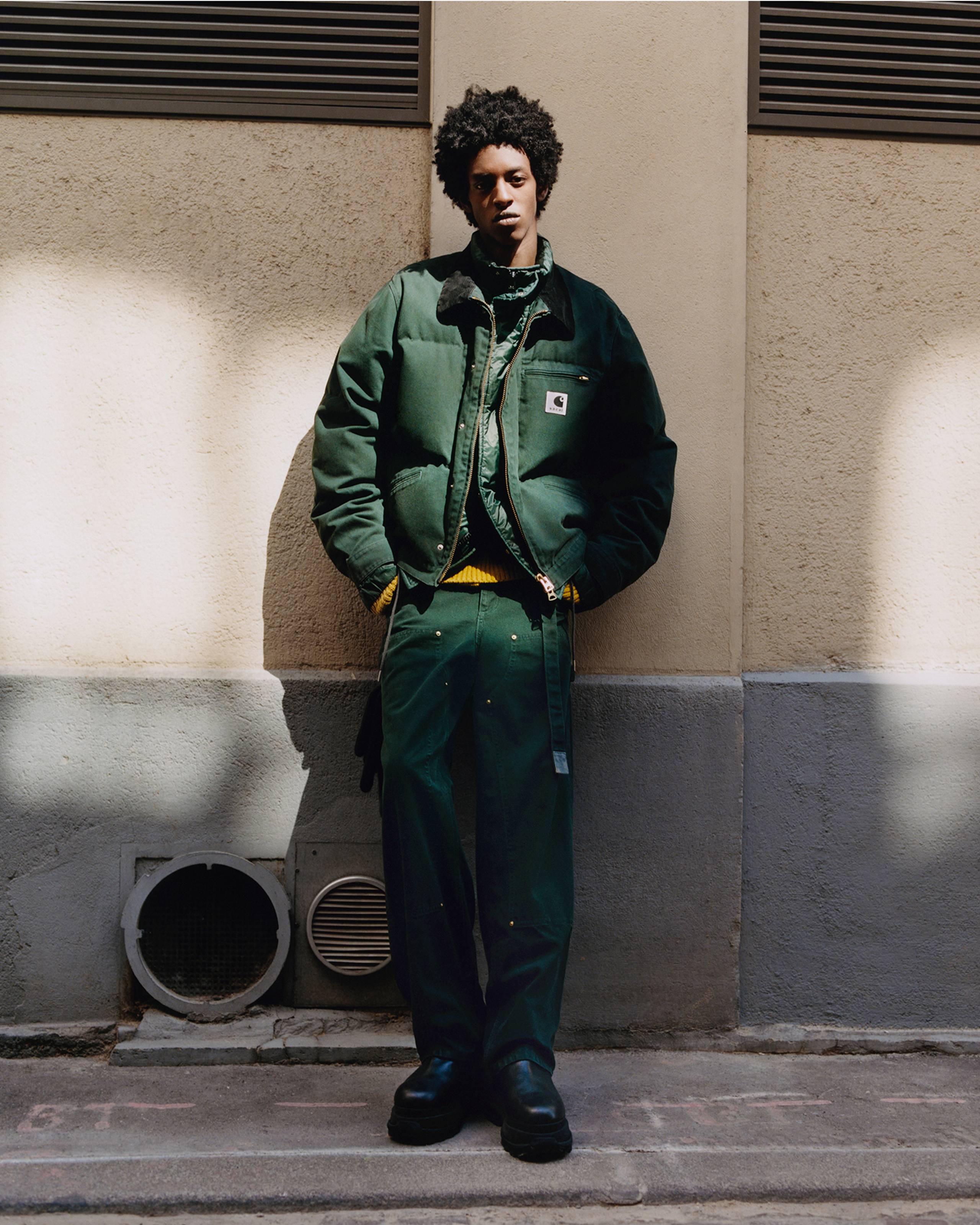 Person wearing a green sacai x Carhartt WIP zip up puffer jacket and green double knee pants