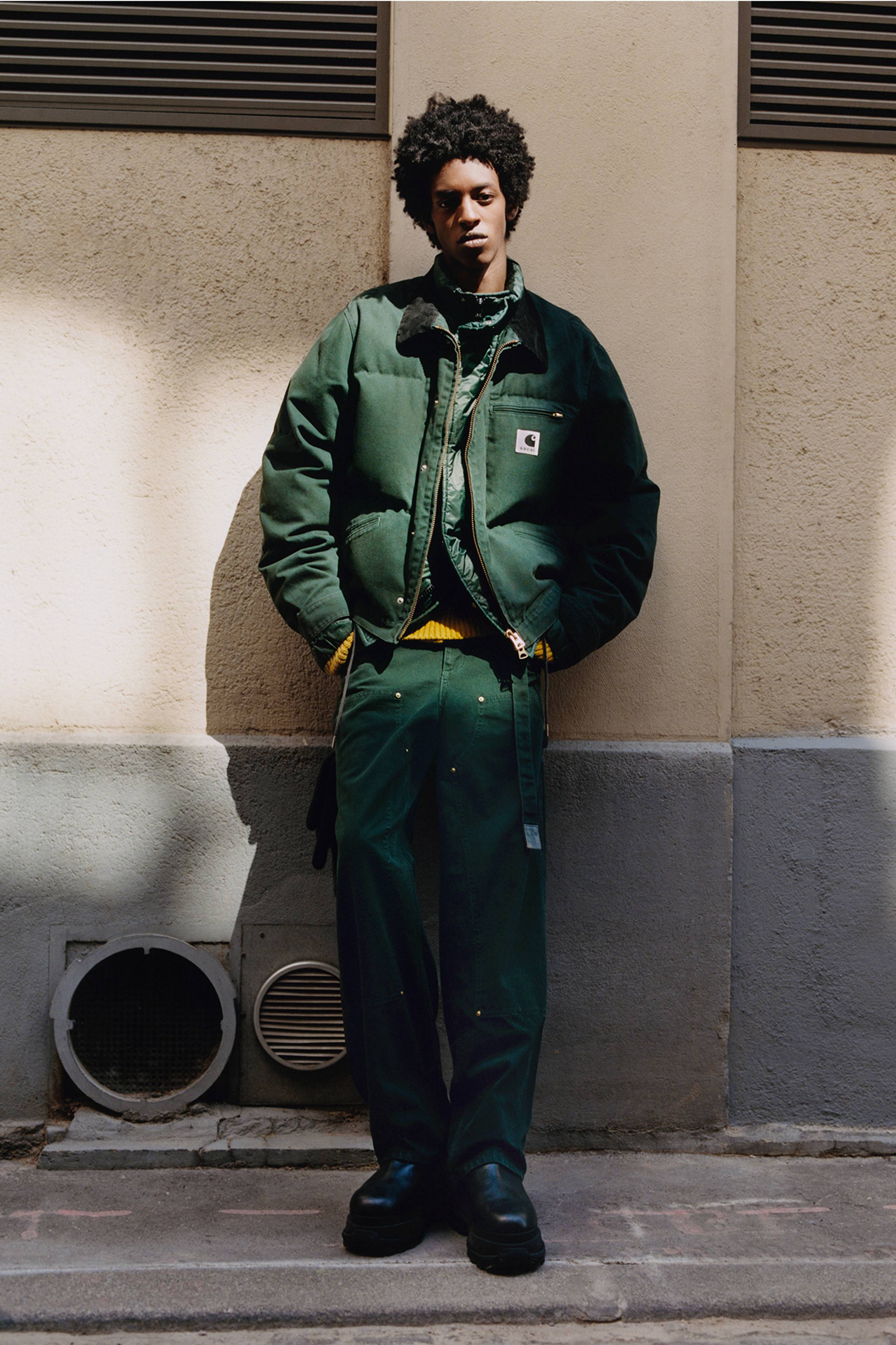 Person wearing a green sacai x Carhartt WIP zip up puffer jacket and green double knee pants