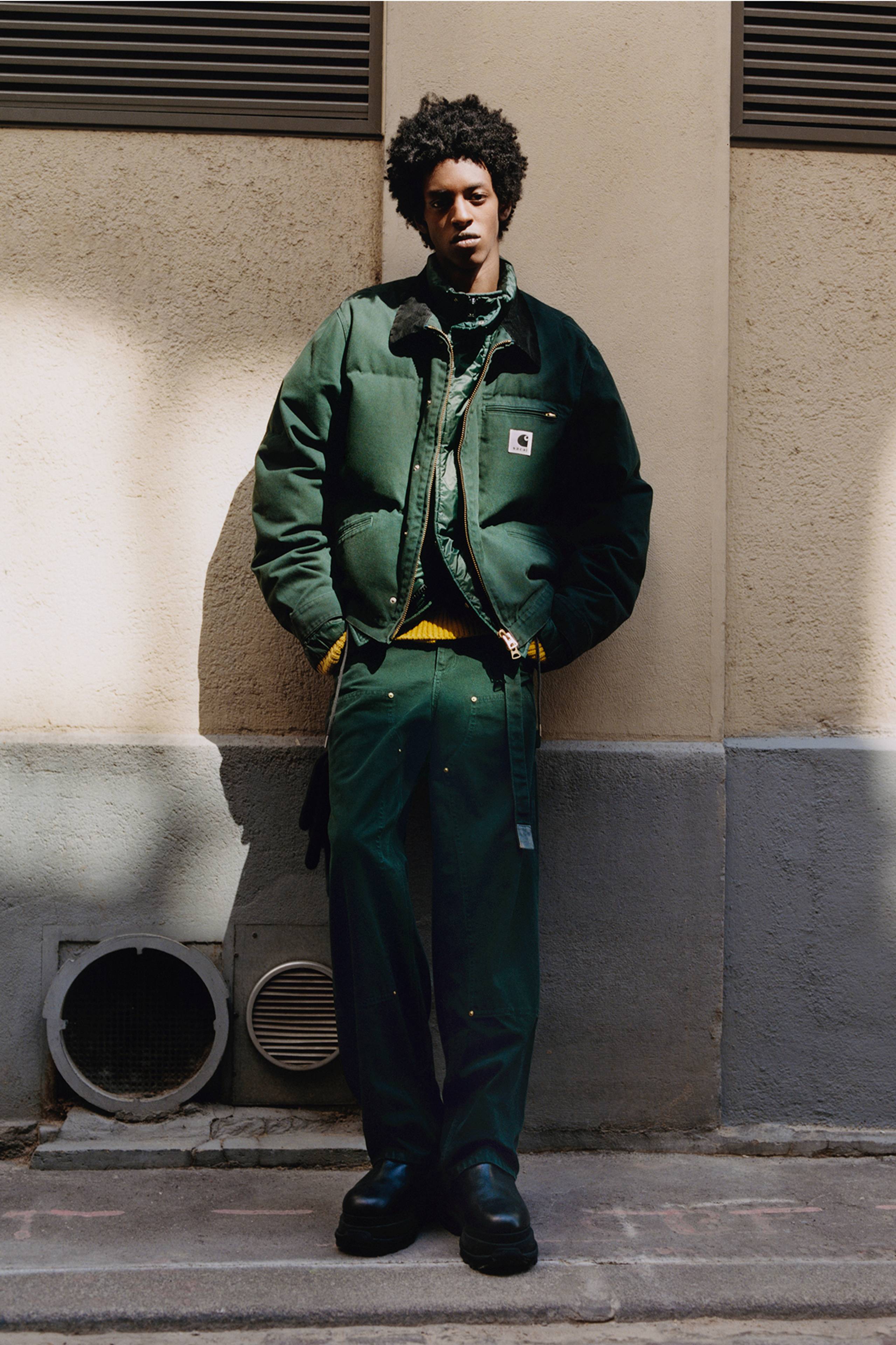 Person wearing a green sacai x Carhartt WIP zip up puffer jacket and green double knee pants
