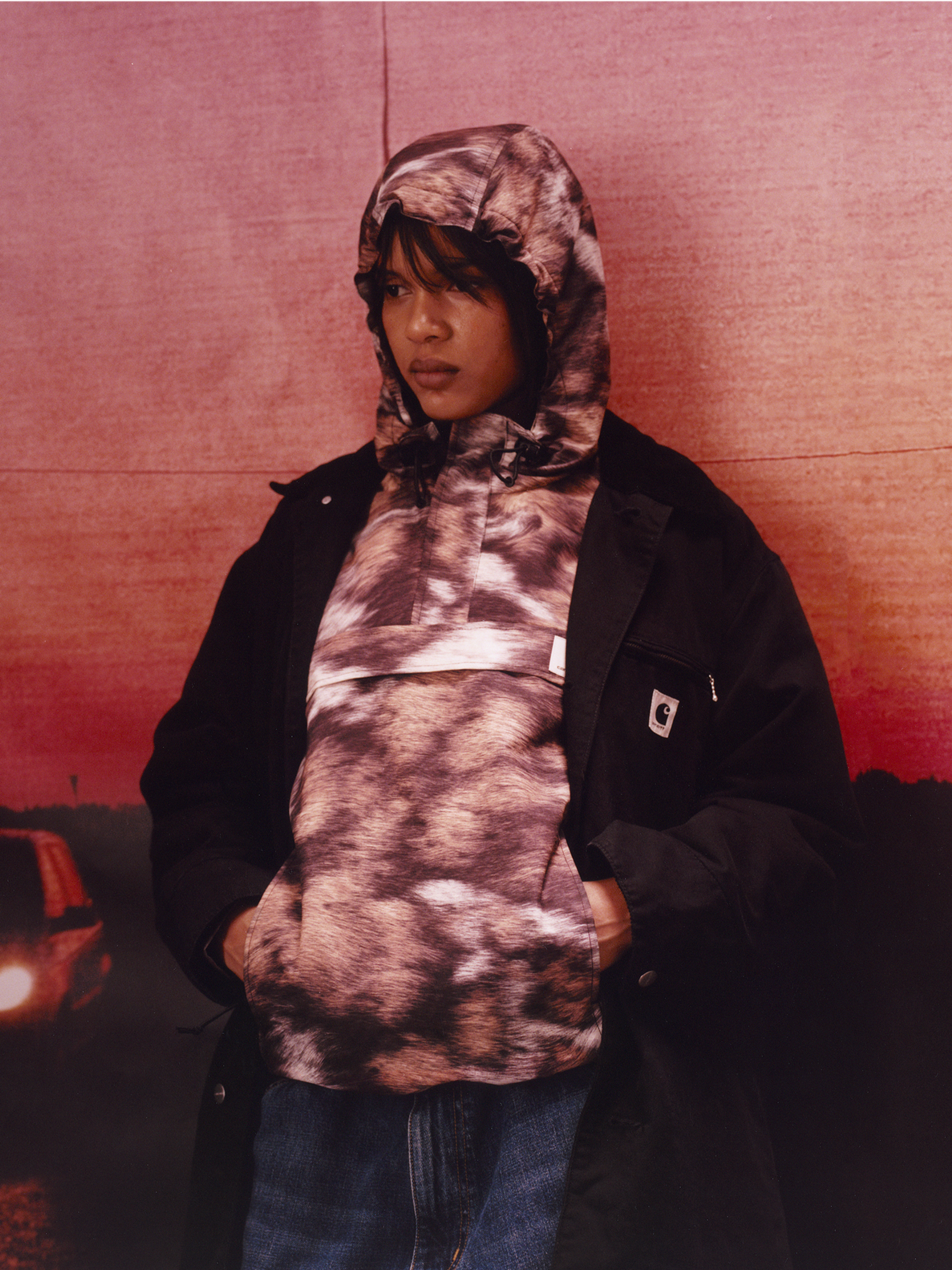 Model wearing a wild dog print jacket and black long coat in the Carhartt WIP F/W25 Women's Lookbook