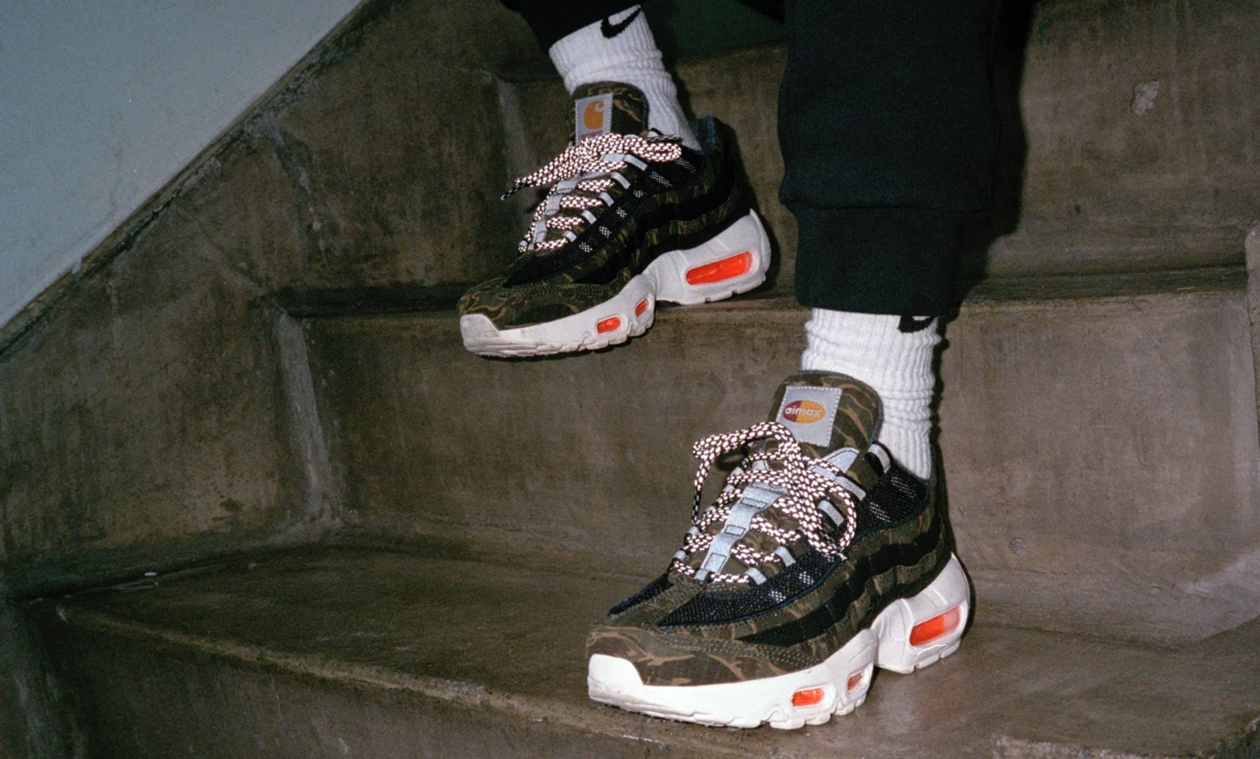 Model wearing Camo Carhartt WIP x Nike Air Max 95 sneakers in a staircase