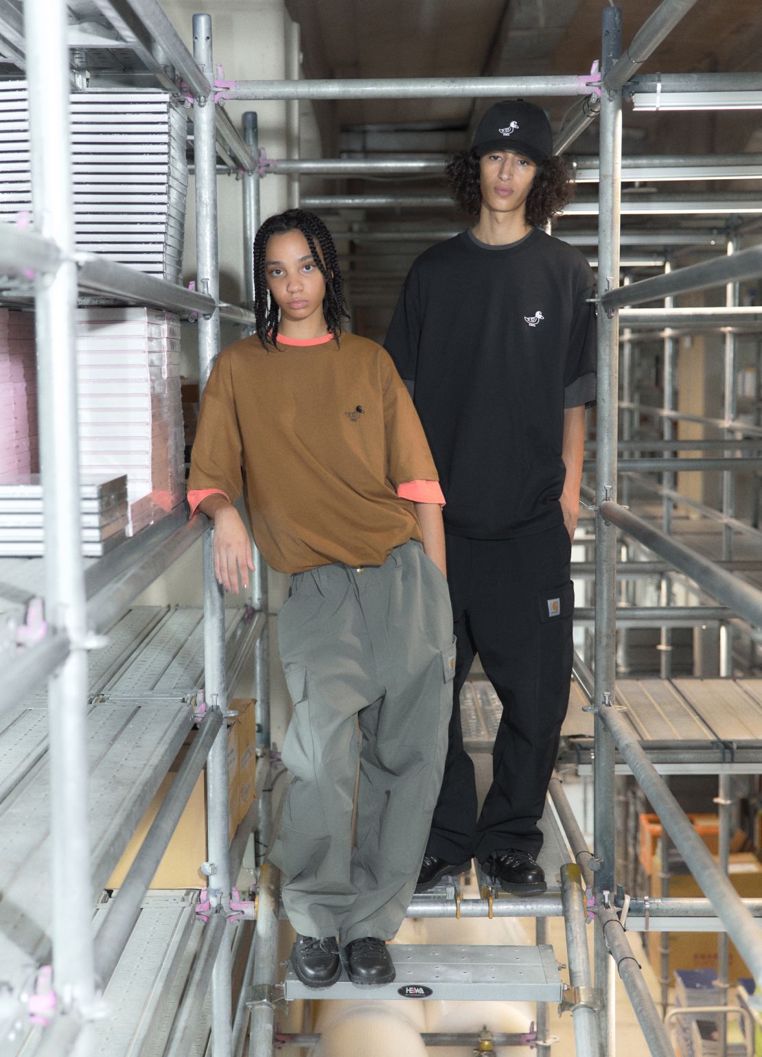 Male & female models wearing Carhartt WIP x INVINCIBLE collection in construction site