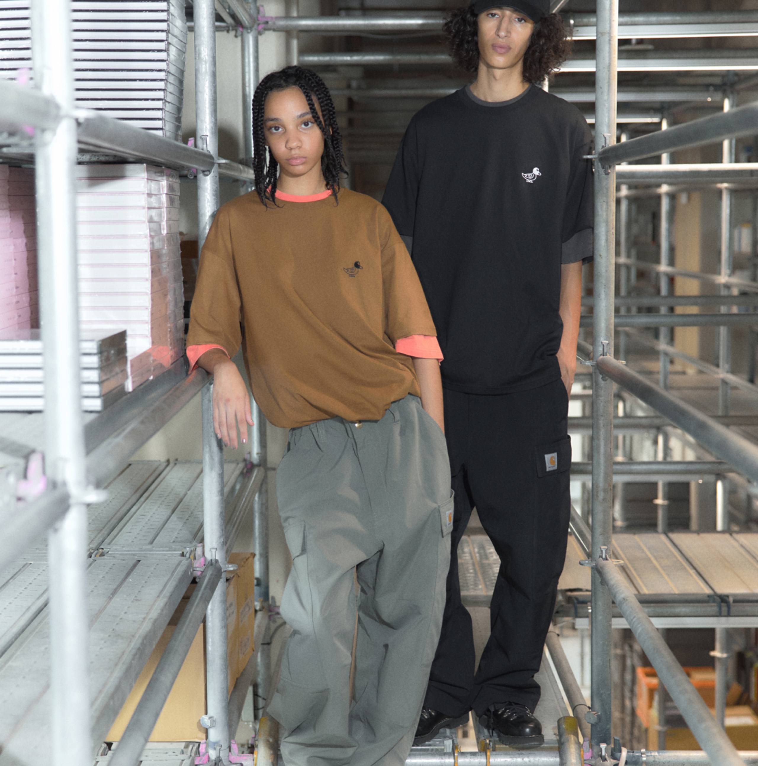 Male & female models wearing Carhartt WIP x INVINCIBLE collection in construction site