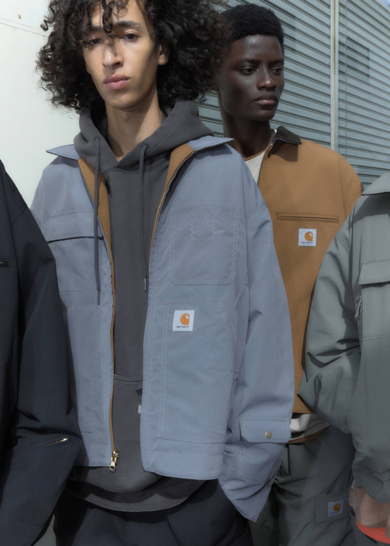 Models wearing items from the Carhartt WIP x INVINCIBLE® collection outside a warehouse