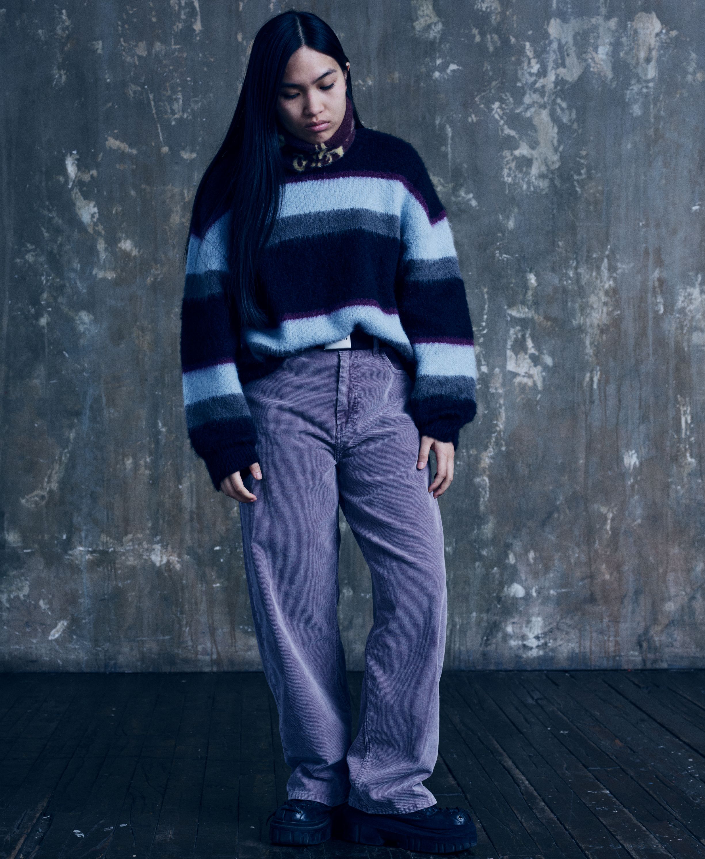 Model wearing a Women’s Merlin Sweater in Citadel and a pair of purple pants
