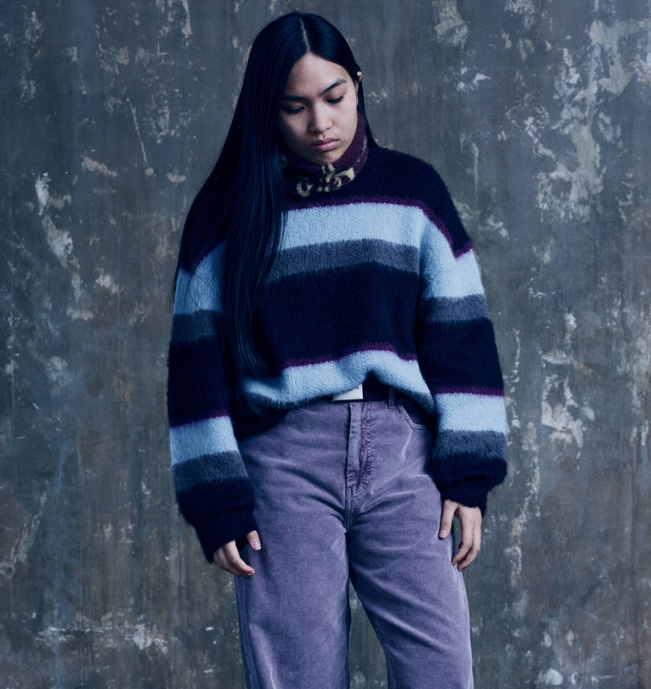 Model wearing a Women’s Merlin Sweater in Citadel and a pair of purple pants