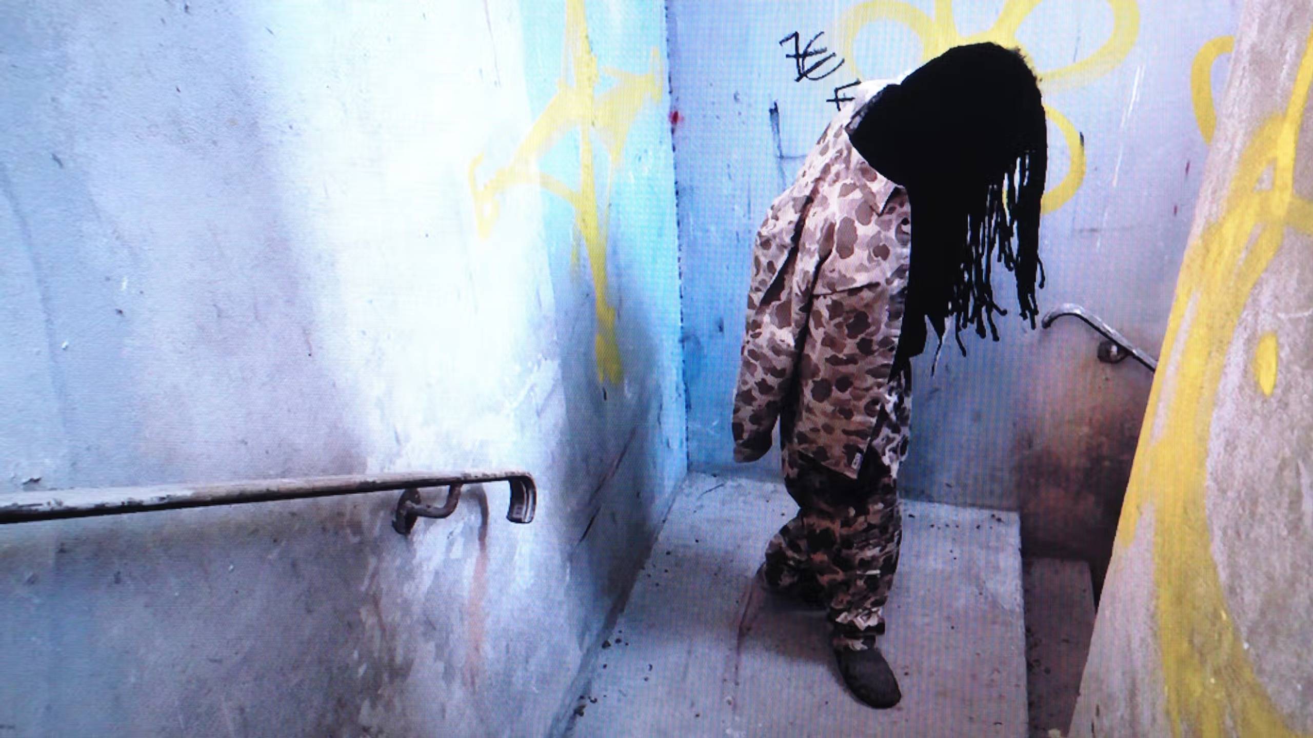 Person wearing a camouflage jacket and pants in a stairwell