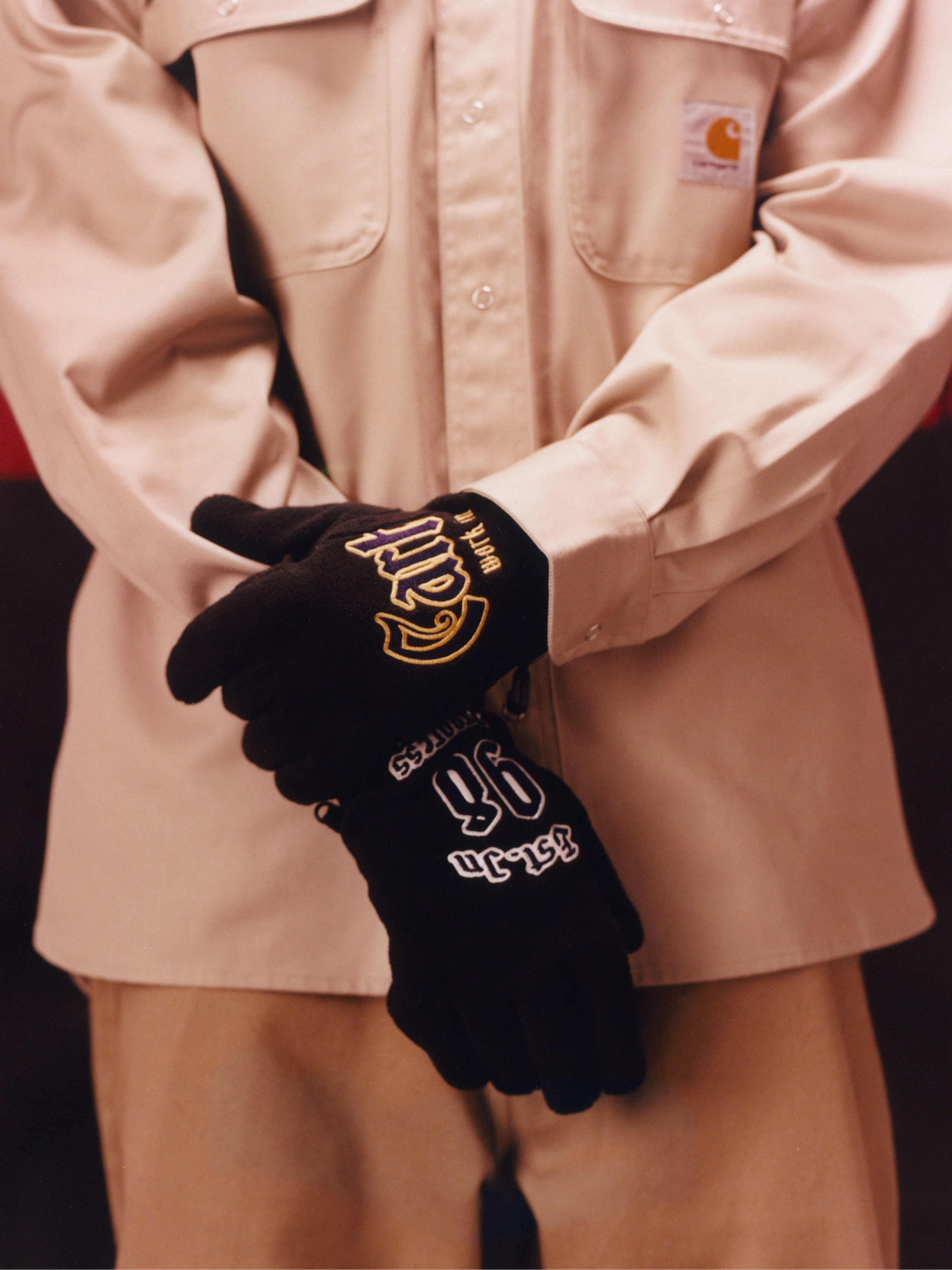 Model wearing a tan shirt and graphic gloves in the Carhartt WIP F/W25 Men's Lookbook