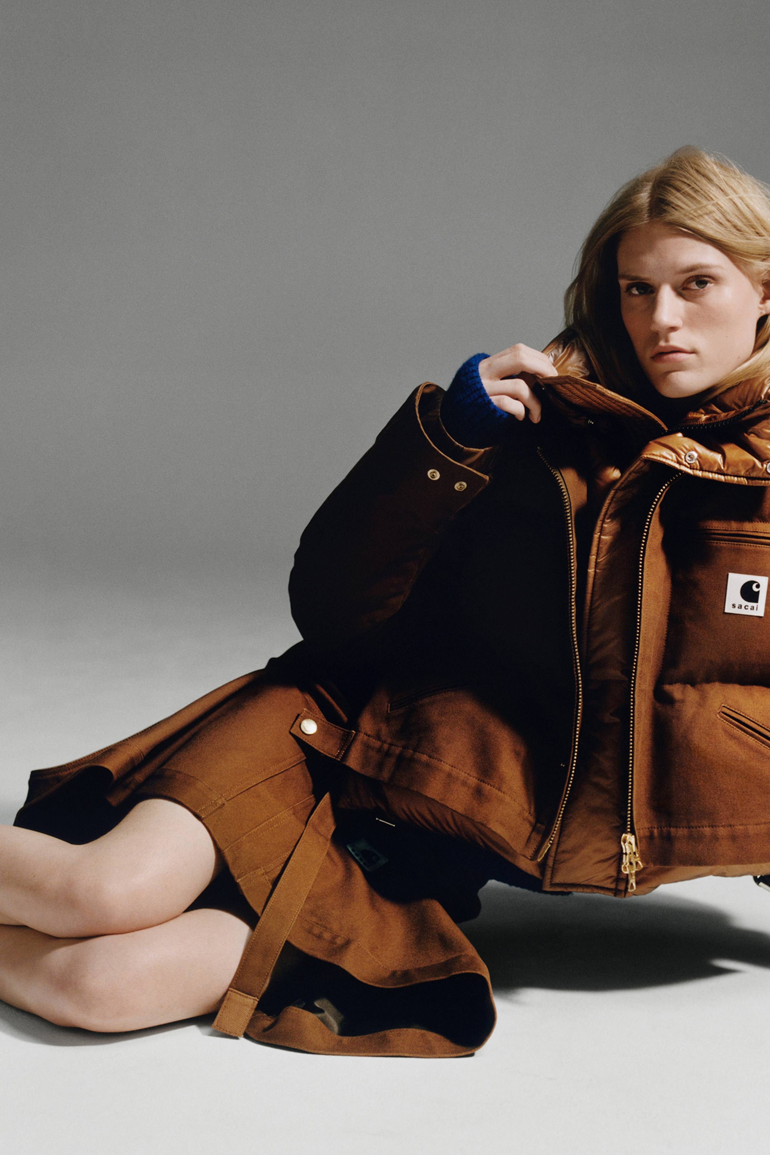 Person wearing a brown sacai x Carhartt WIP zip up cropped puffer jacket and brown skirt
