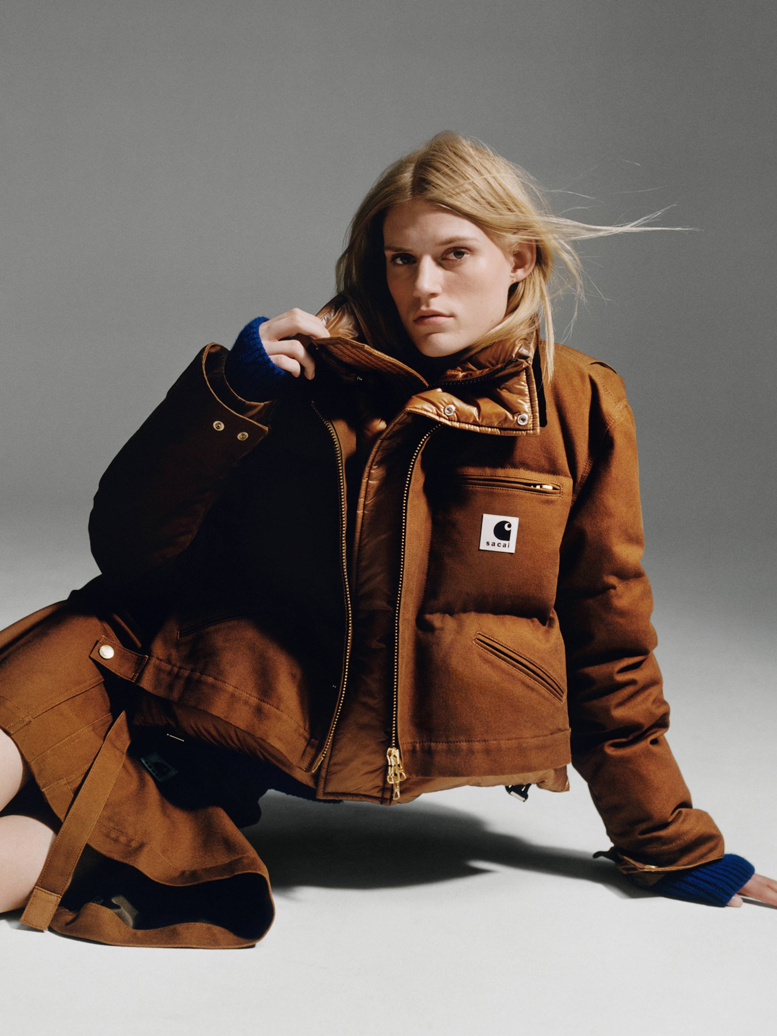 Person wearing a brown sacai x Carhartt WIP zip up cropped puffer jacket and brown skirt