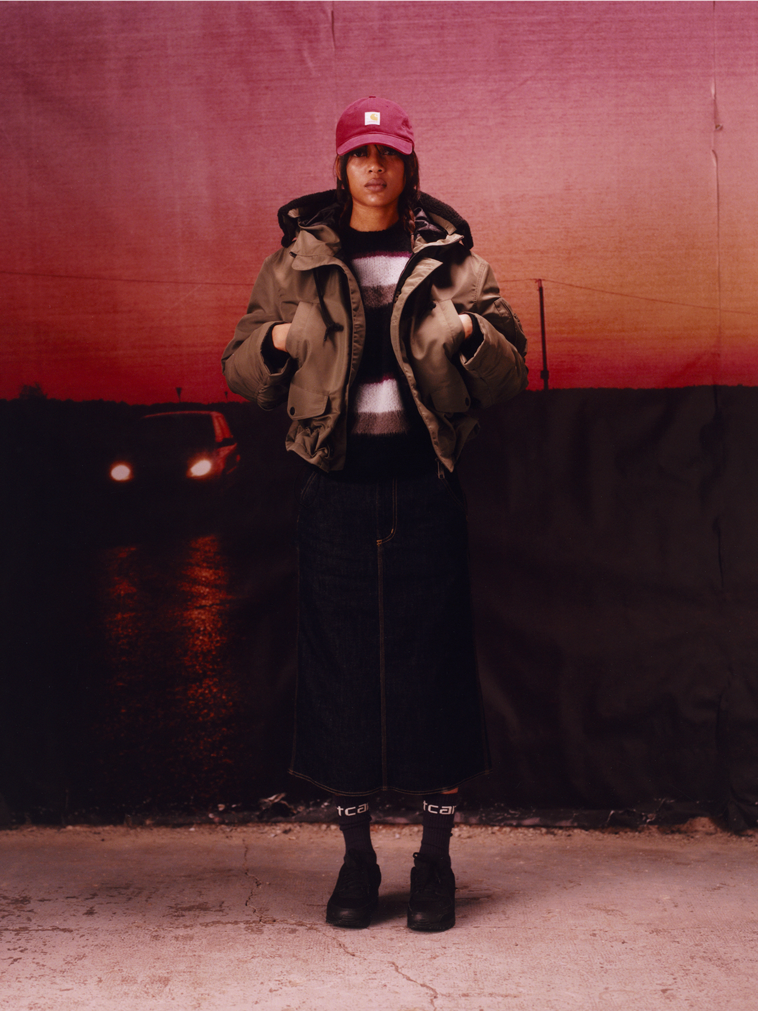 Model wearing a hooded jacket and denim skirt in the Carhartt WIP F/W25 Women's Lookbook
