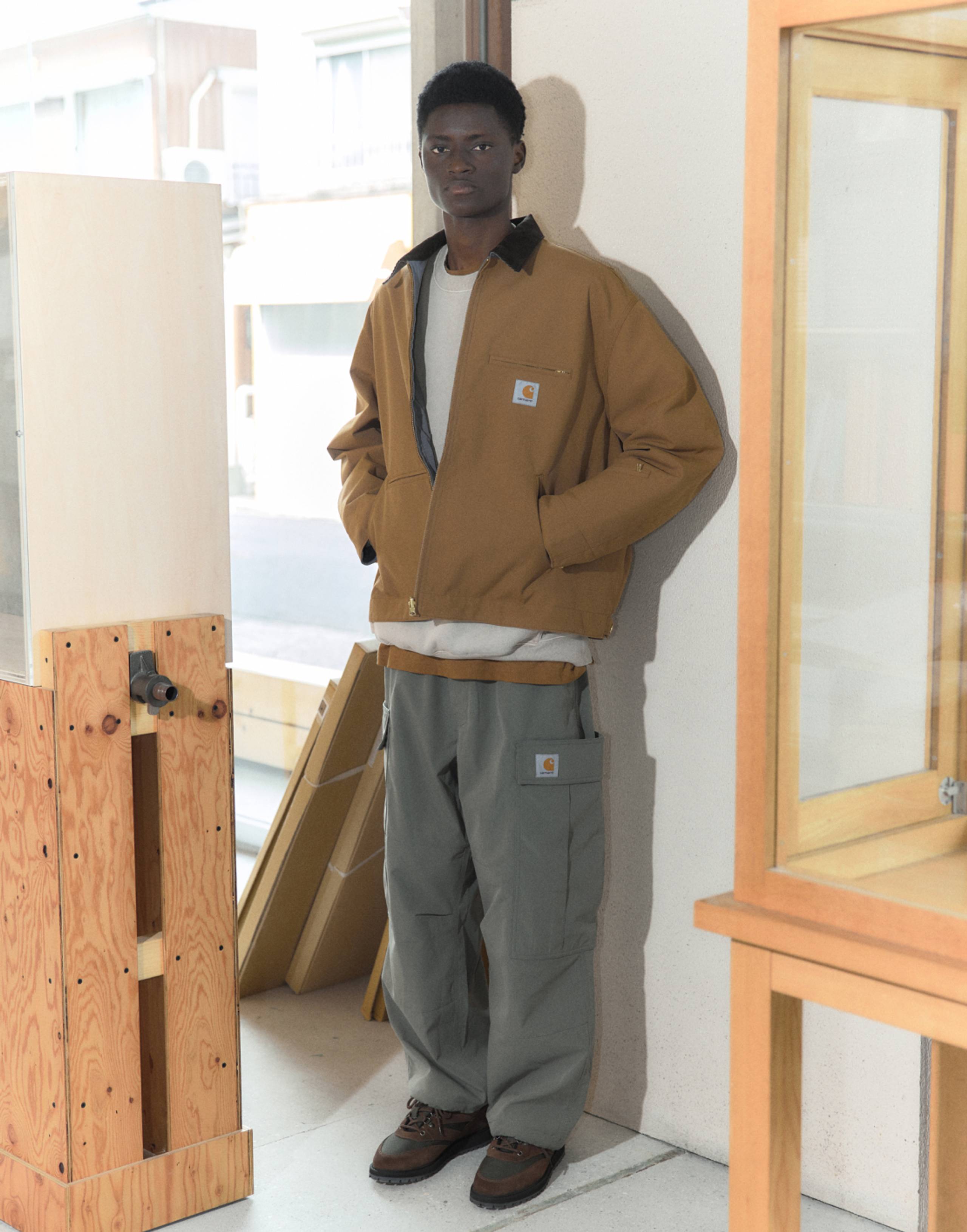 Model wearing Carhartt WIP x INVINCIBLE® Reversible Detroit Jacket Max in Hamilton Brown